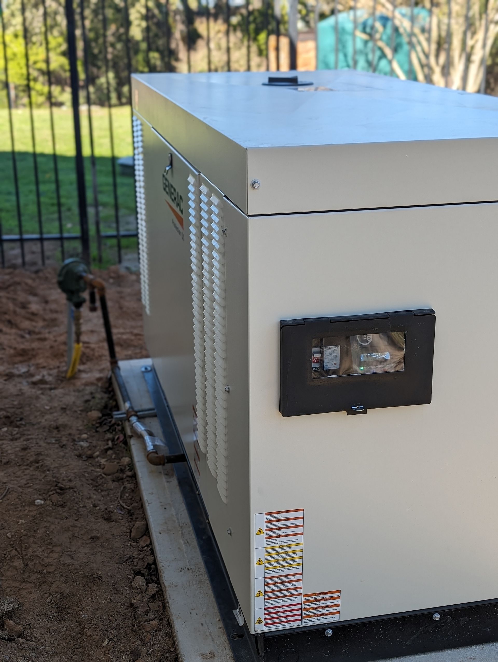 A generator is sitting on the ground next to a fence.