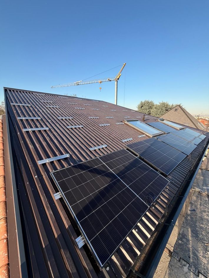 Pannelli solari installati su un tetto di tegole, con vista su un paesaggio suburbano sotto un cielo nuvoloso.