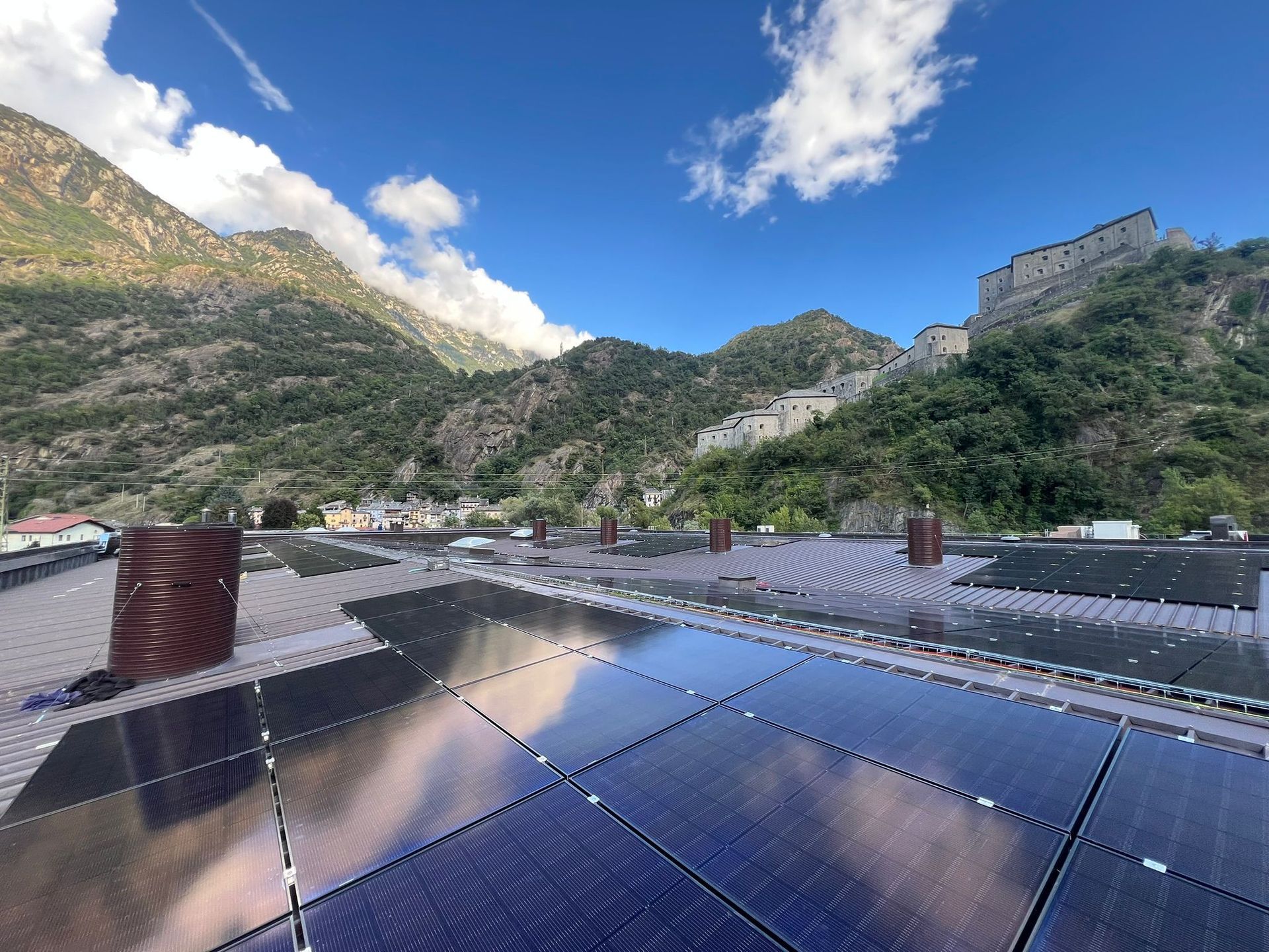 Pannelli solari sui tetti in una valle di montagna sotto un cielo azzurro con nuvole