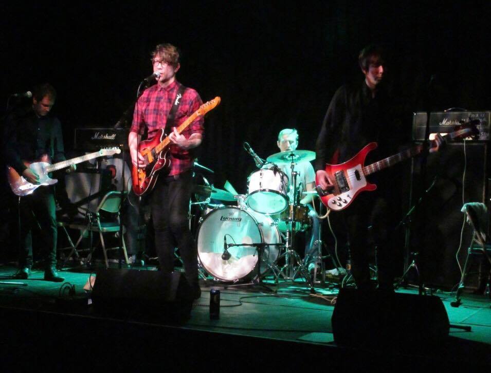 A group of people playing guitars and drums on a stage