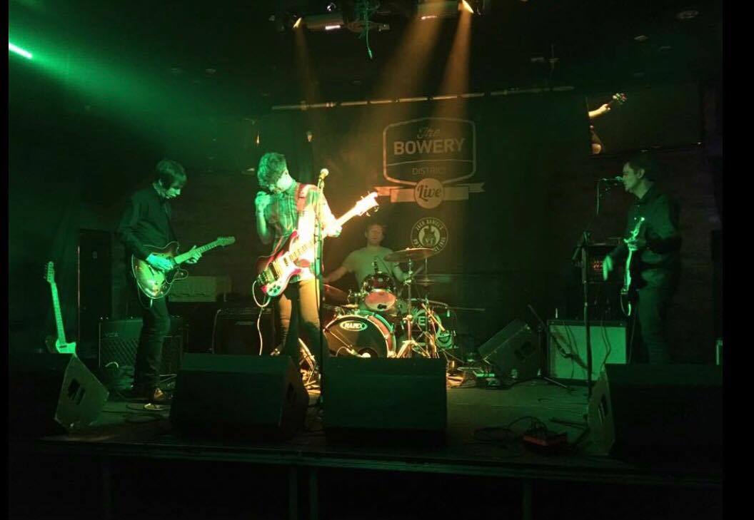 A group of people are playing instruments on a stage in a dark room.