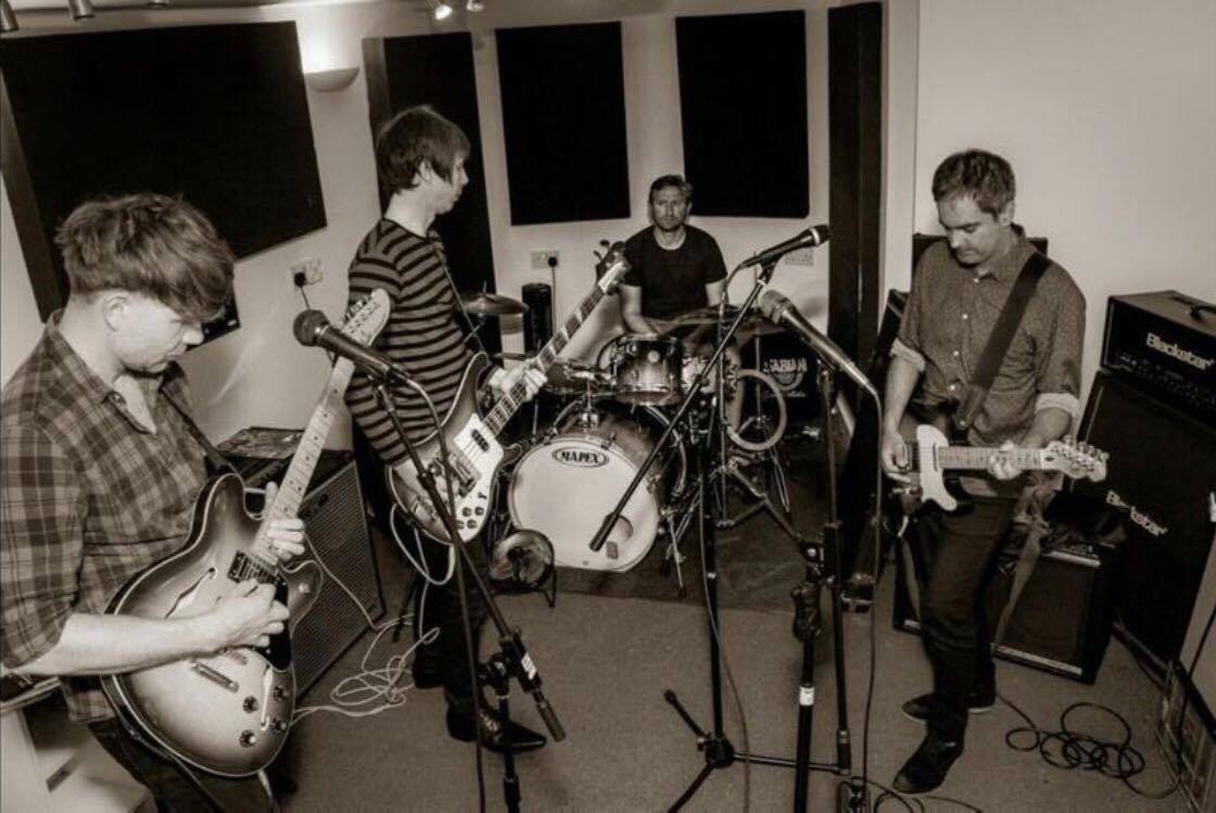 A group of men are playing guitars and drums in a room.
