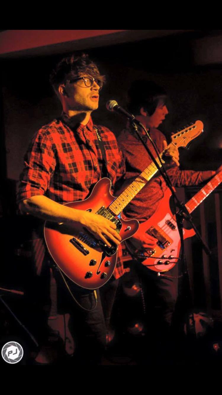 A man is playing a guitar and singing into a microphone on stage.
