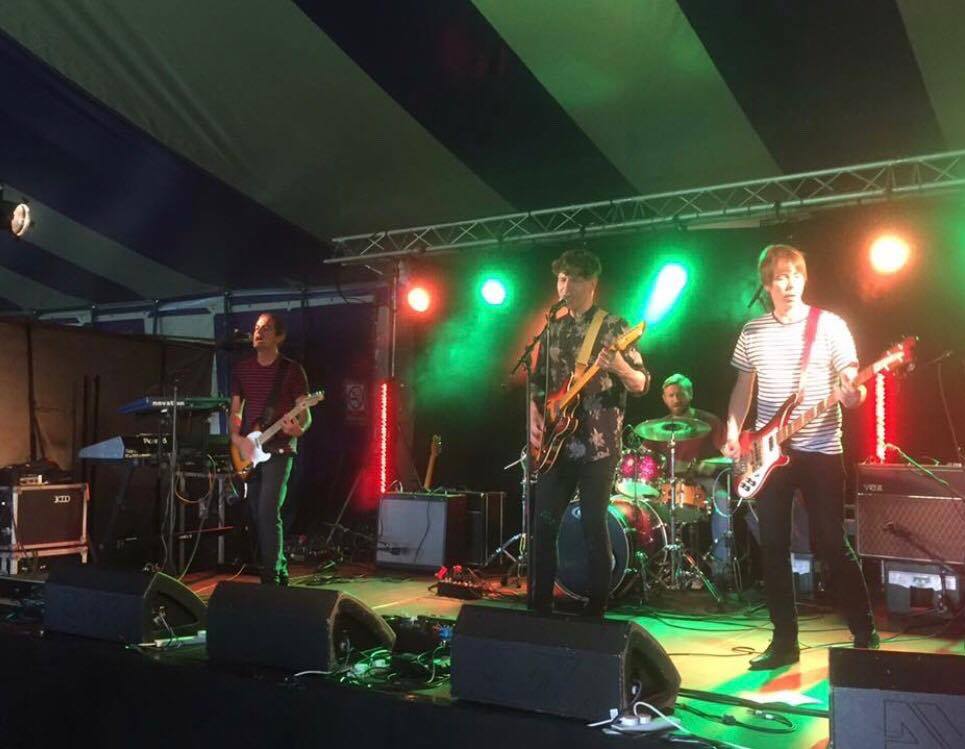 A group of men are playing guitars and singing on a stage.