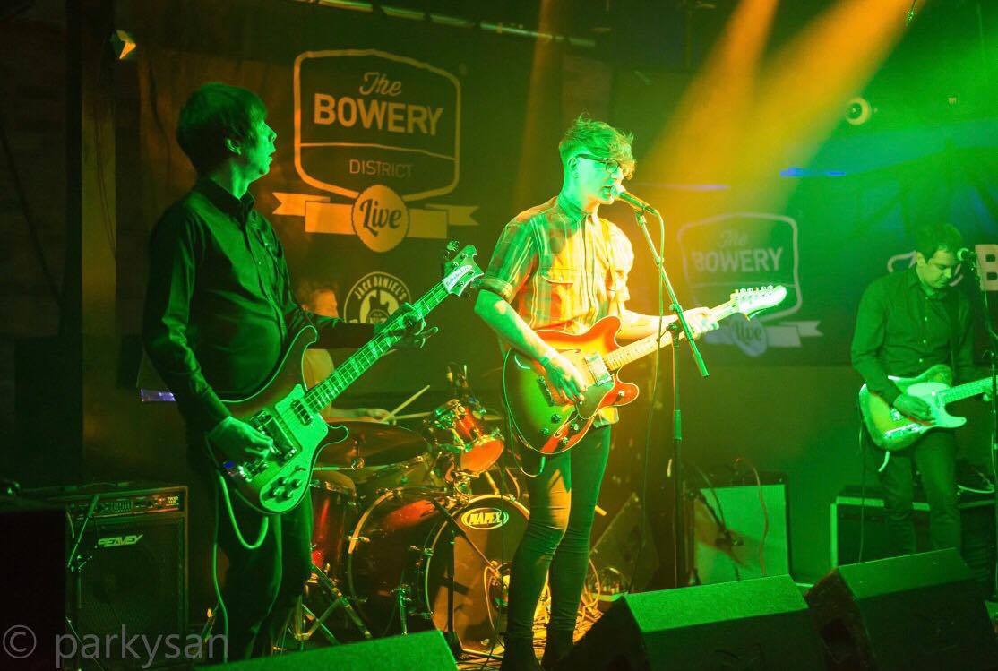 A group of men are playing guitars and singing on a stage.