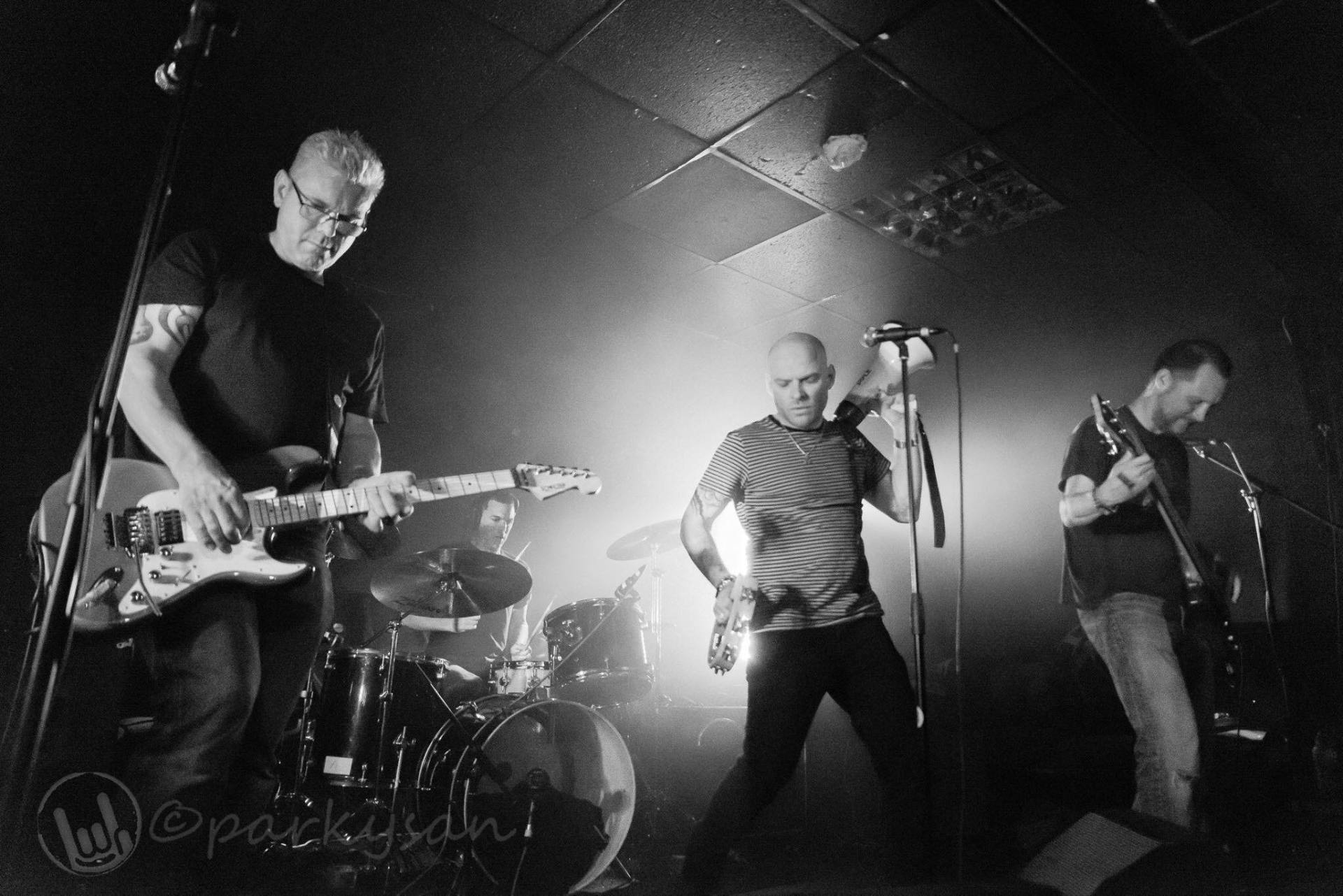 A group of men are playing guitars and singing into microphones on a stage.