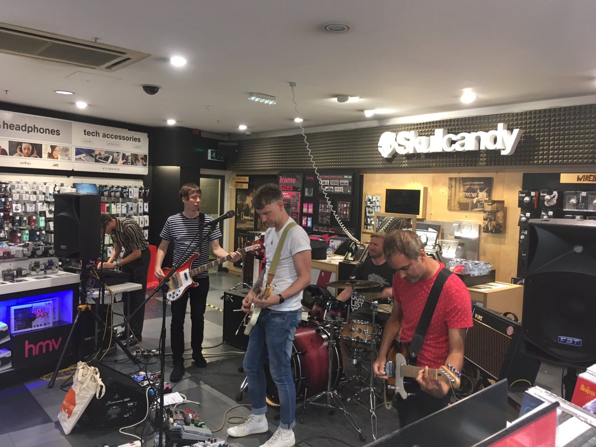 A group of men are playing guitars and drums in a store.