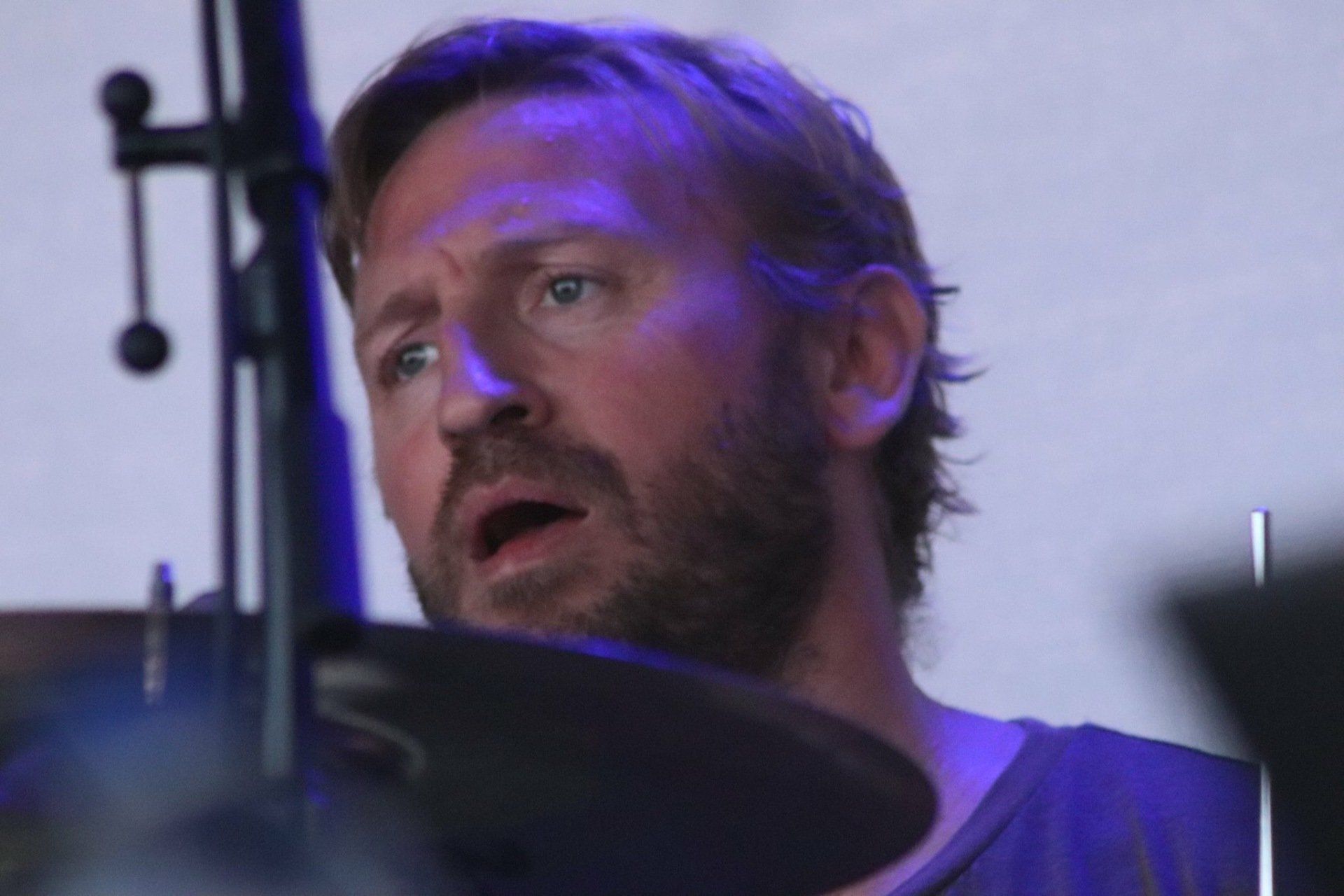 A man with a beard is playing drums on a stage.