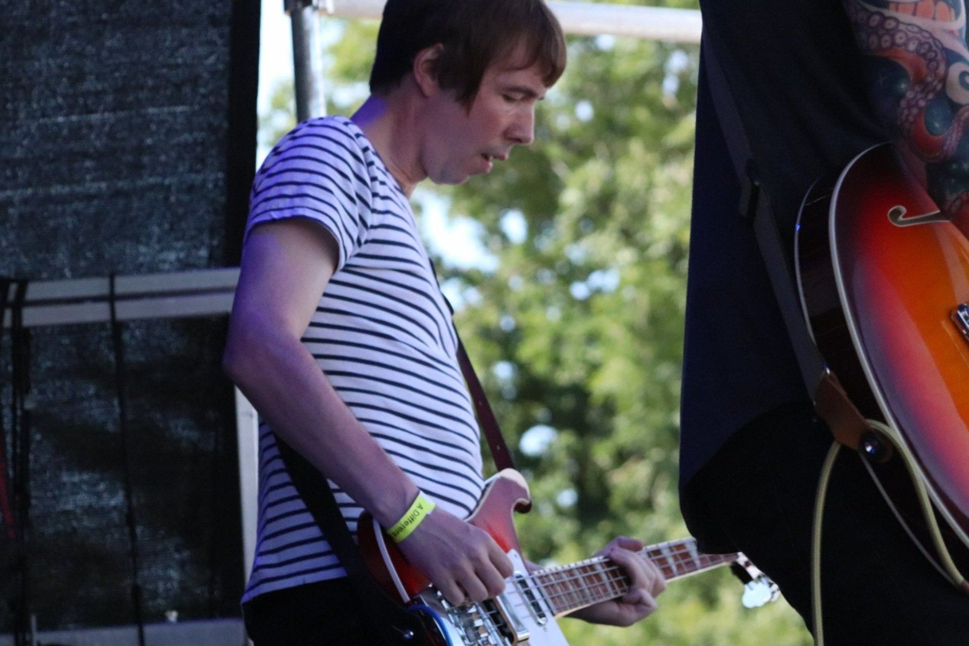 A man in a striped shirt is playing a guitar