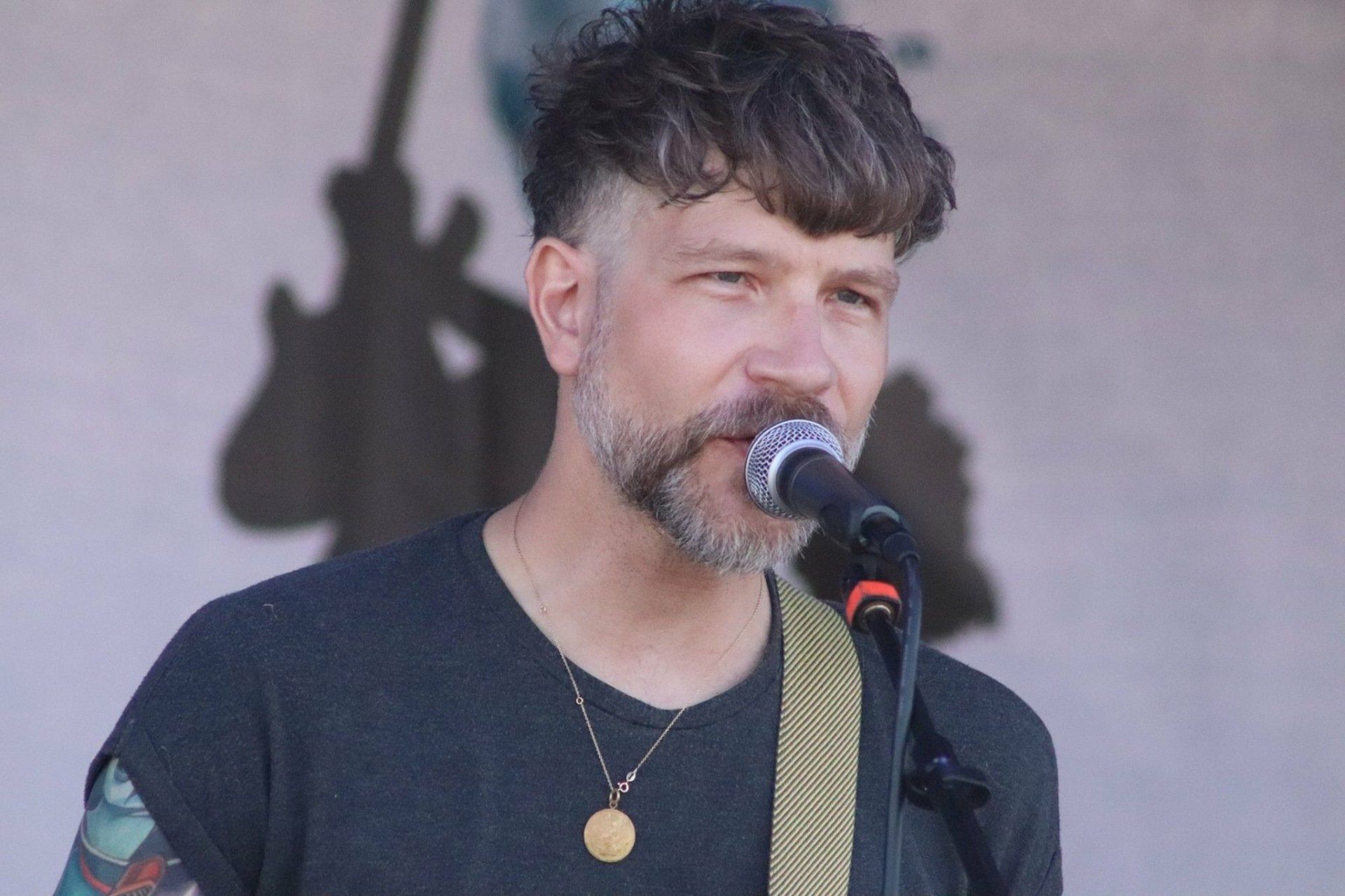 A man with a beard is singing into a microphone.