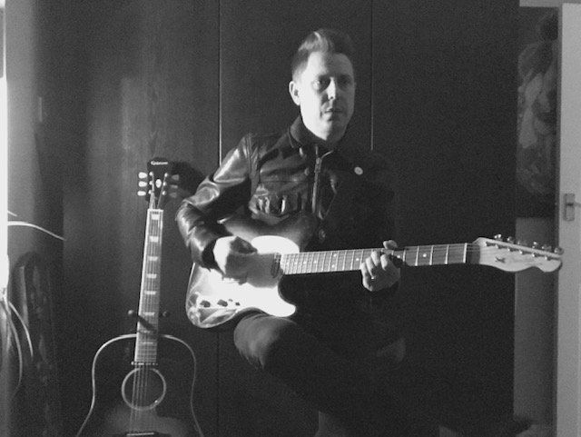 A black and white photo of a man playing a guitar