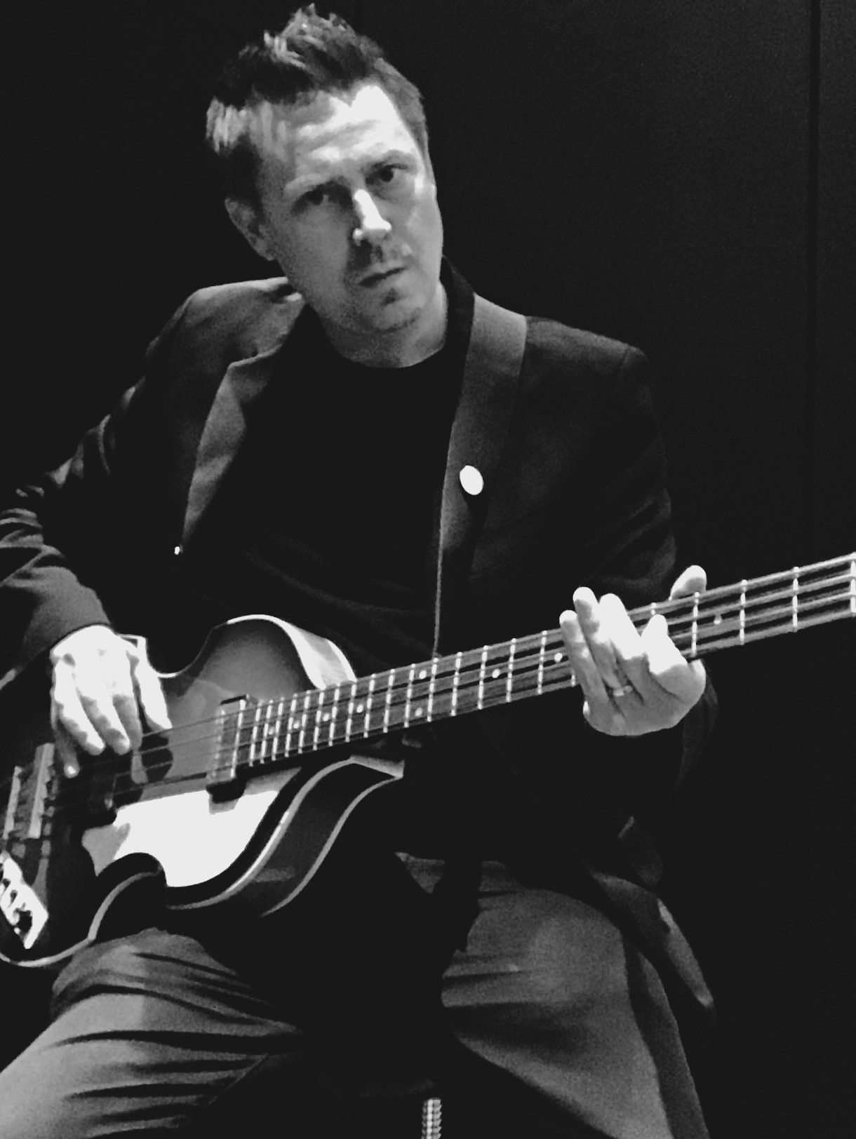 A man in a suit is playing a guitar in a black and white photo