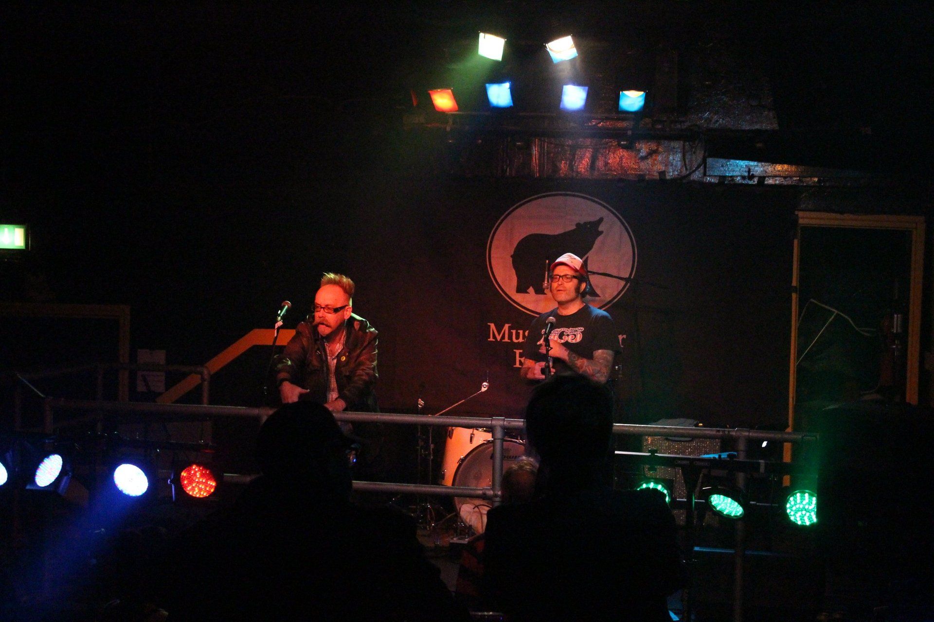 A man playing a guitar and a man playing drums on stage