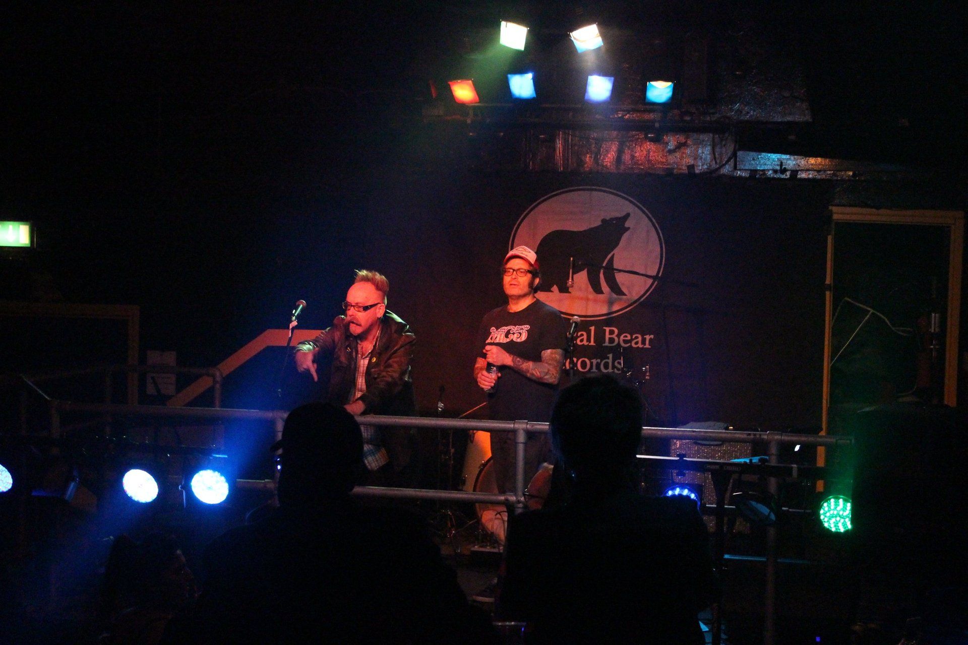 A group of people are standing on a stage in front of a sign that says ' all bear ' on it.