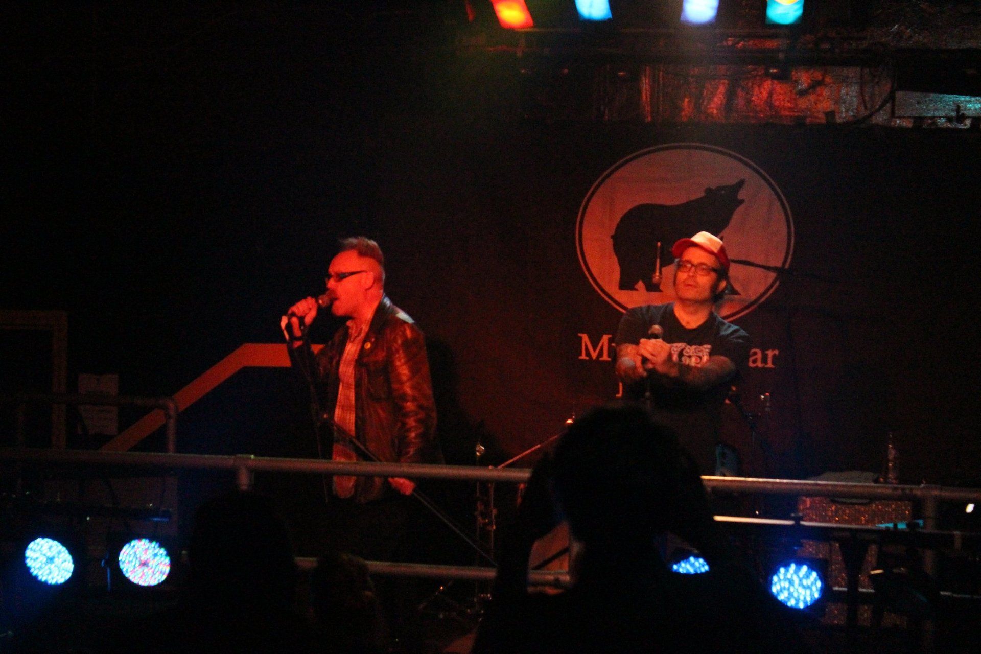 Two men are standing on a stage in front of a sign that says metal bear