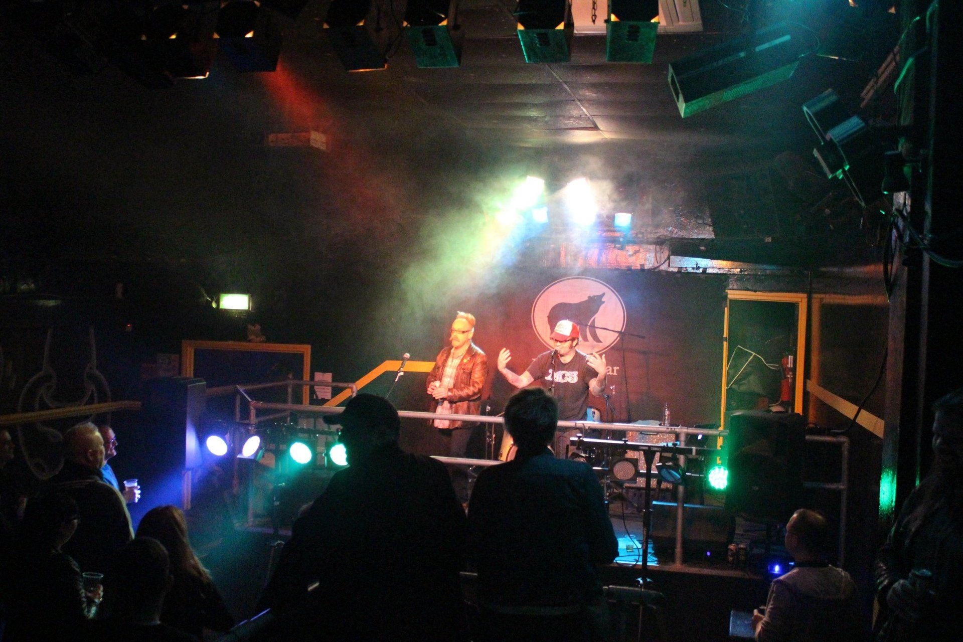 A group of people are watching a band on stage in a dark room