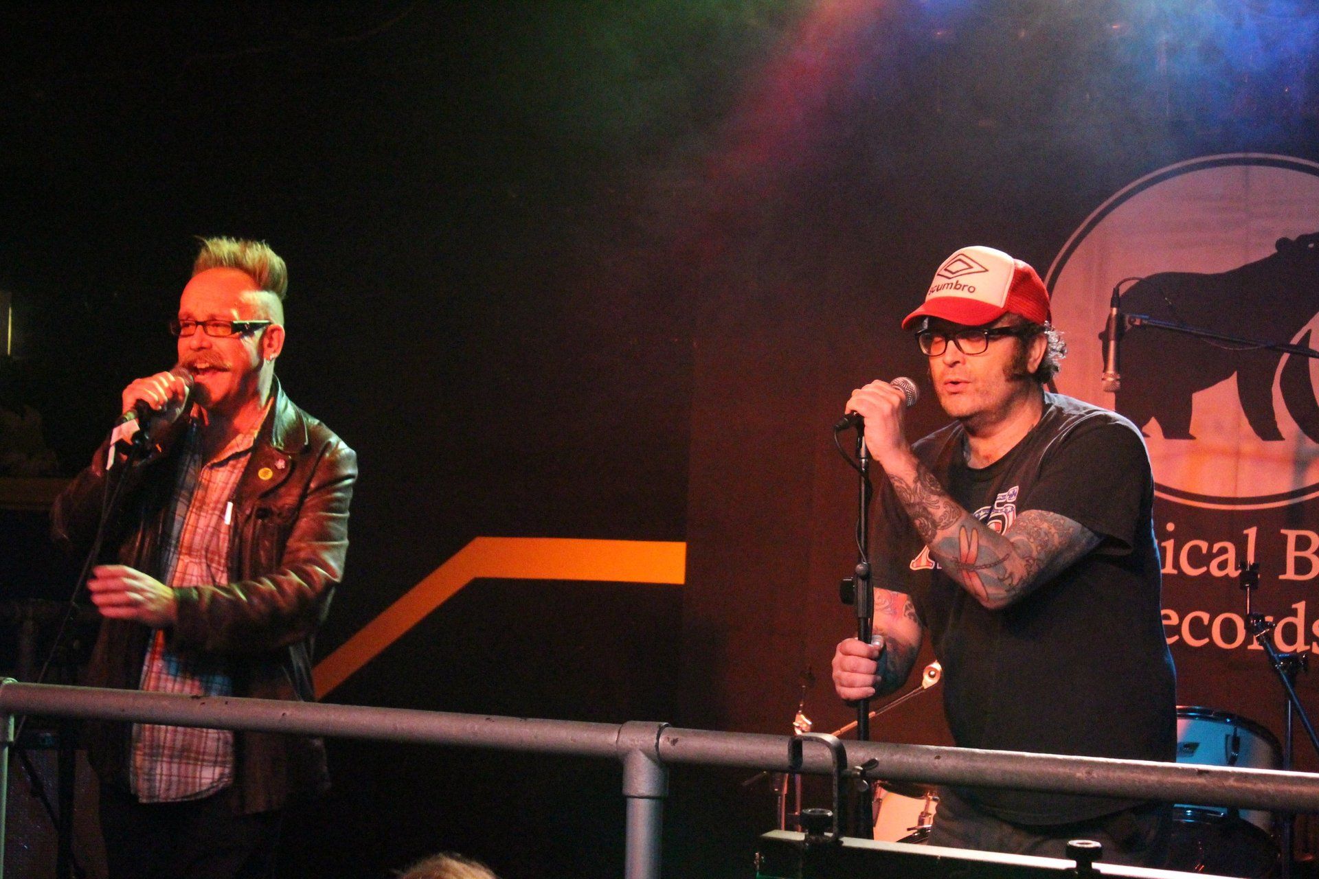 Two men singing into microphones in front of a sign that says ica records
