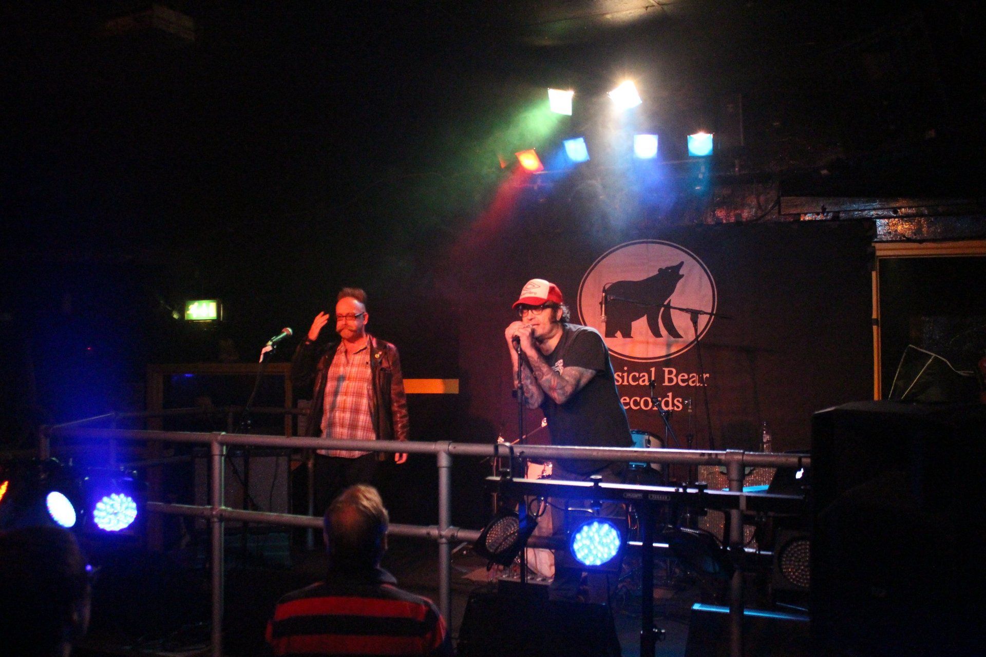 A man singing into a microphone on a stage with a wolf on it