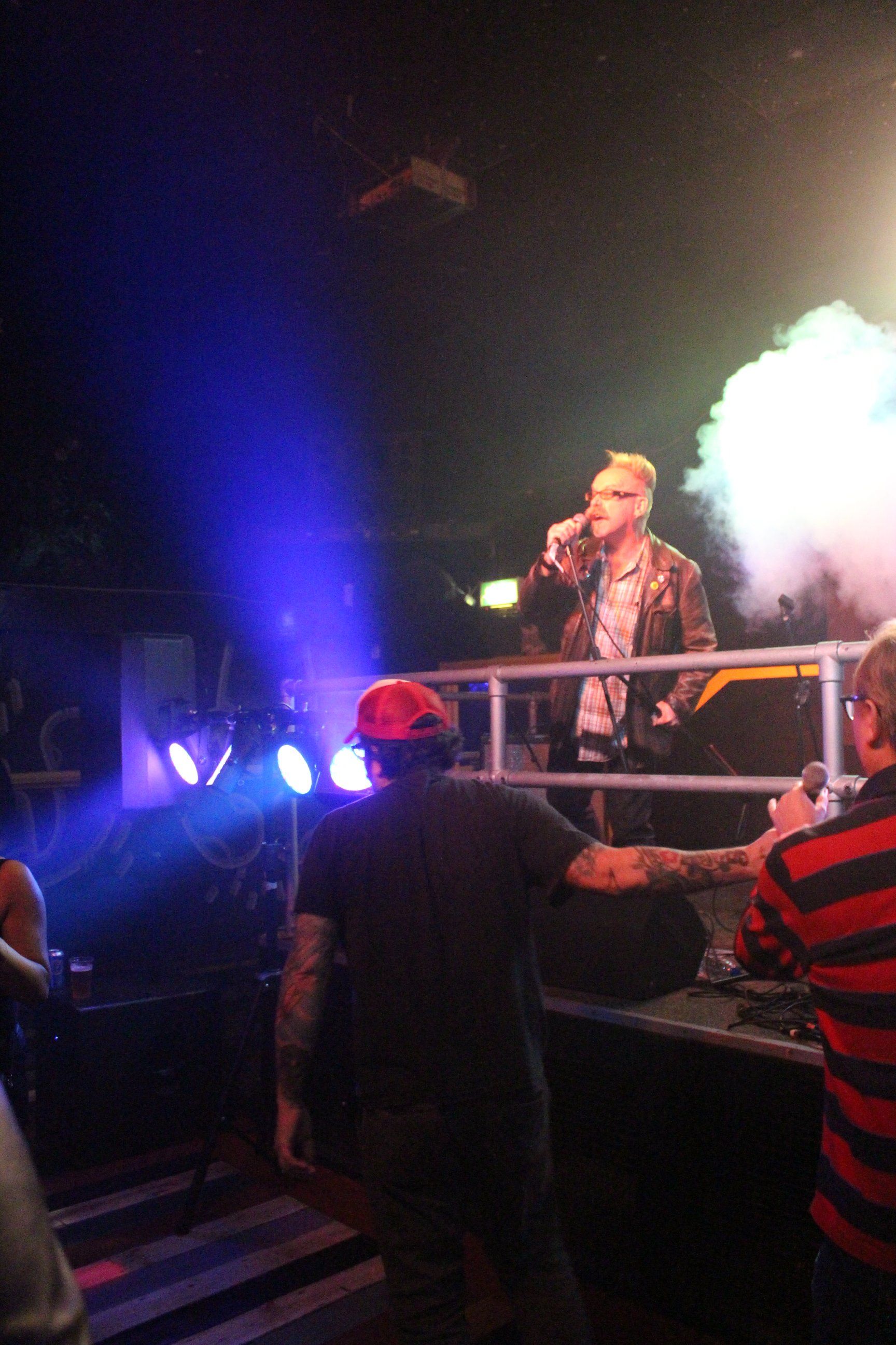 A man singing into a microphone on a stage with smoke coming out of it