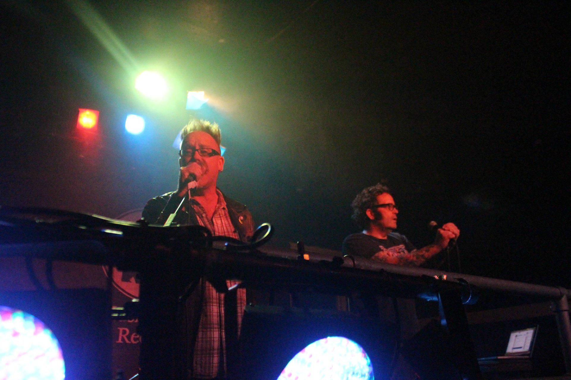 A man singing into a microphone while another man plays a keyboard