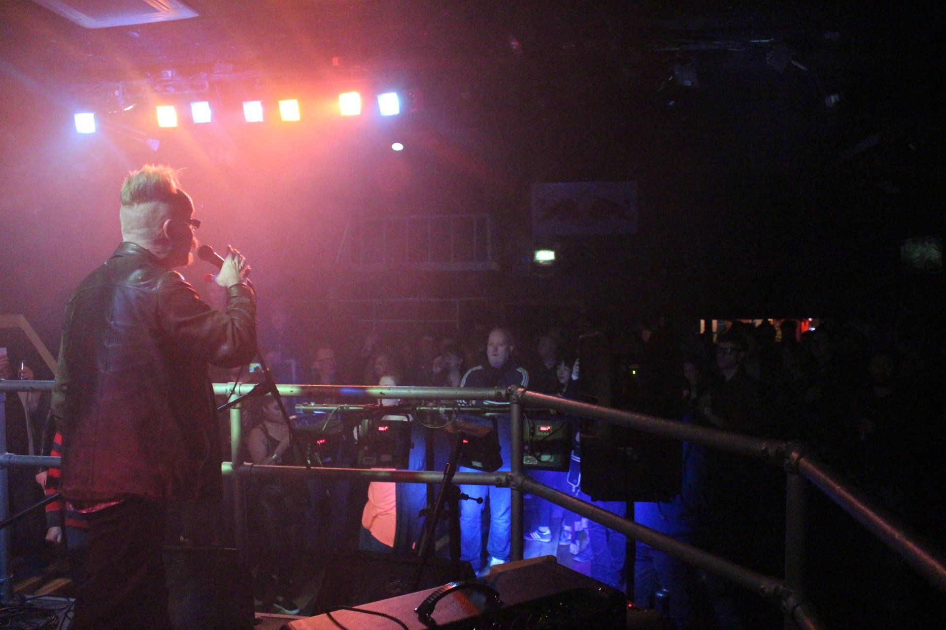 A man is singing into a microphone on a stage in front of a crowd.