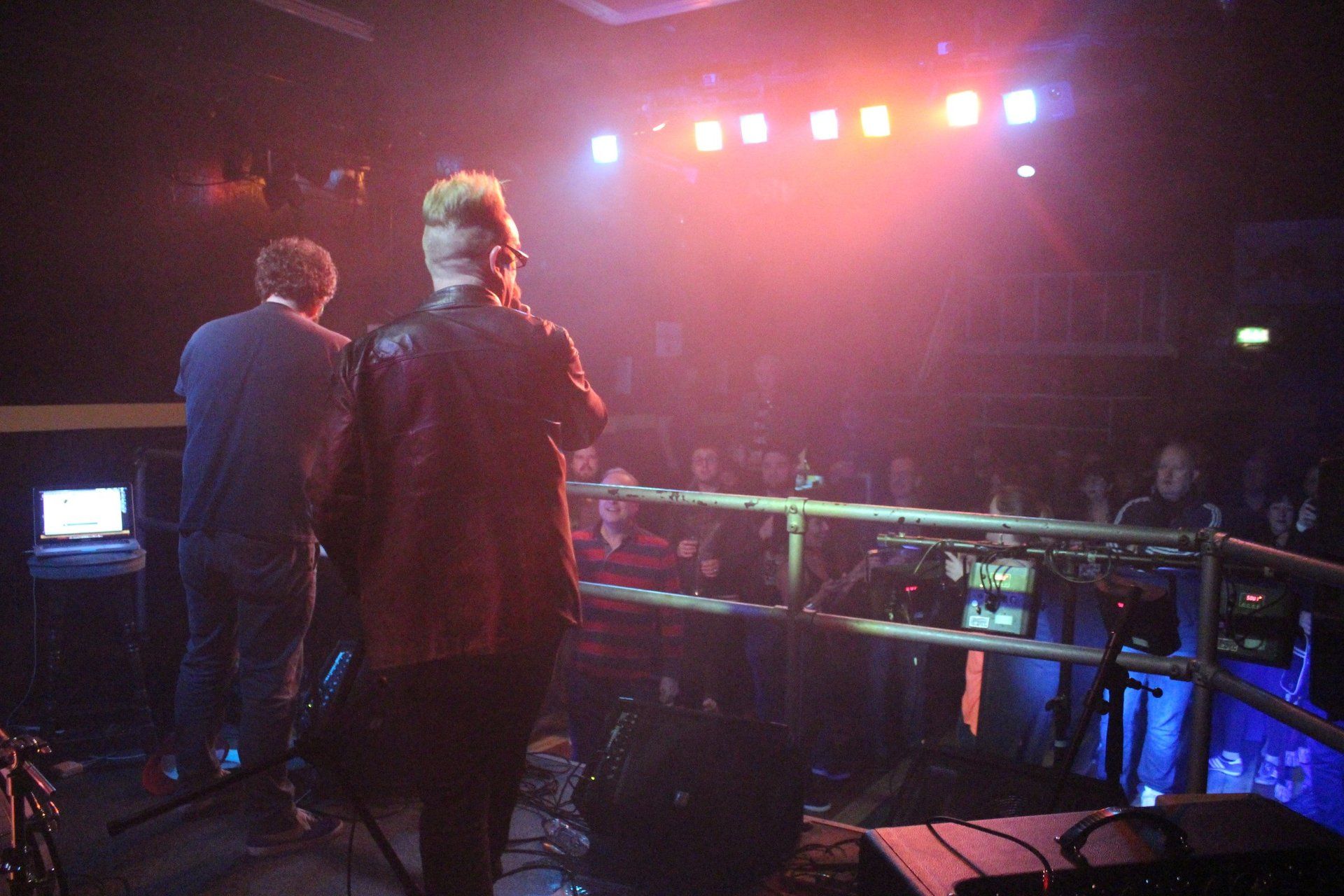 Two men are standing on a stage in front of a crowd.