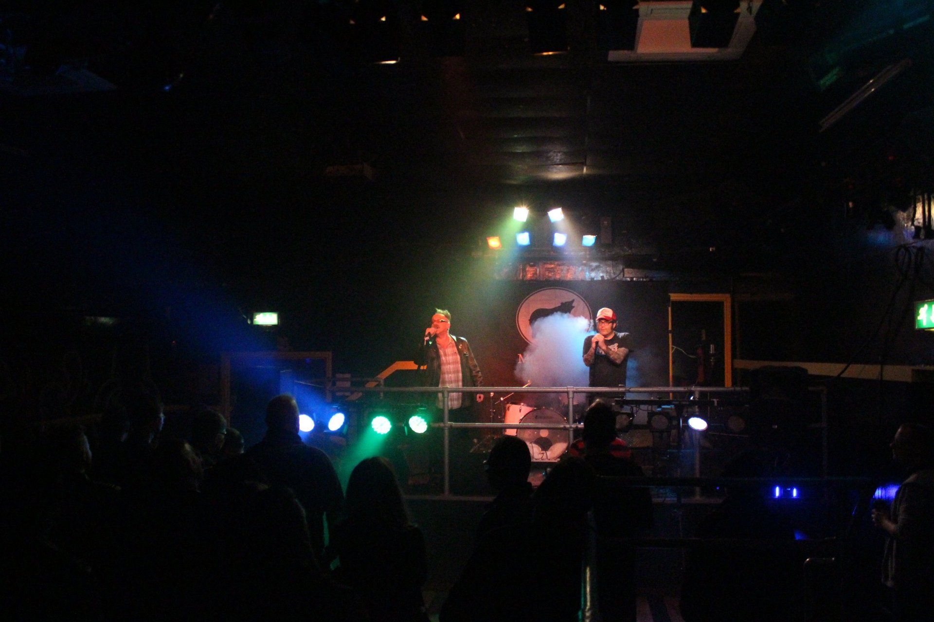 A group of people are standing in front of a stage in a dark room.