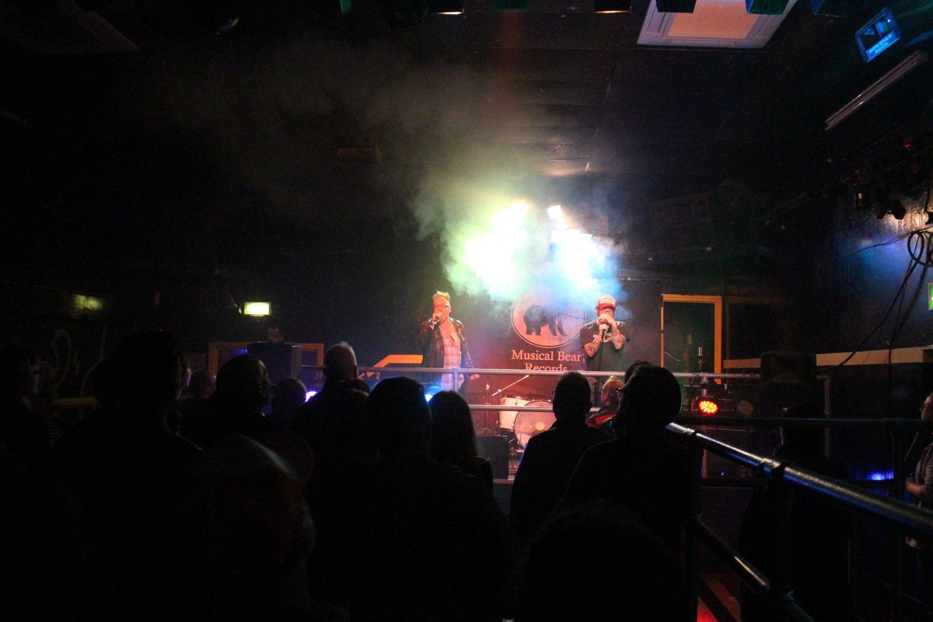 A group of people are watching a concert in a dark room.