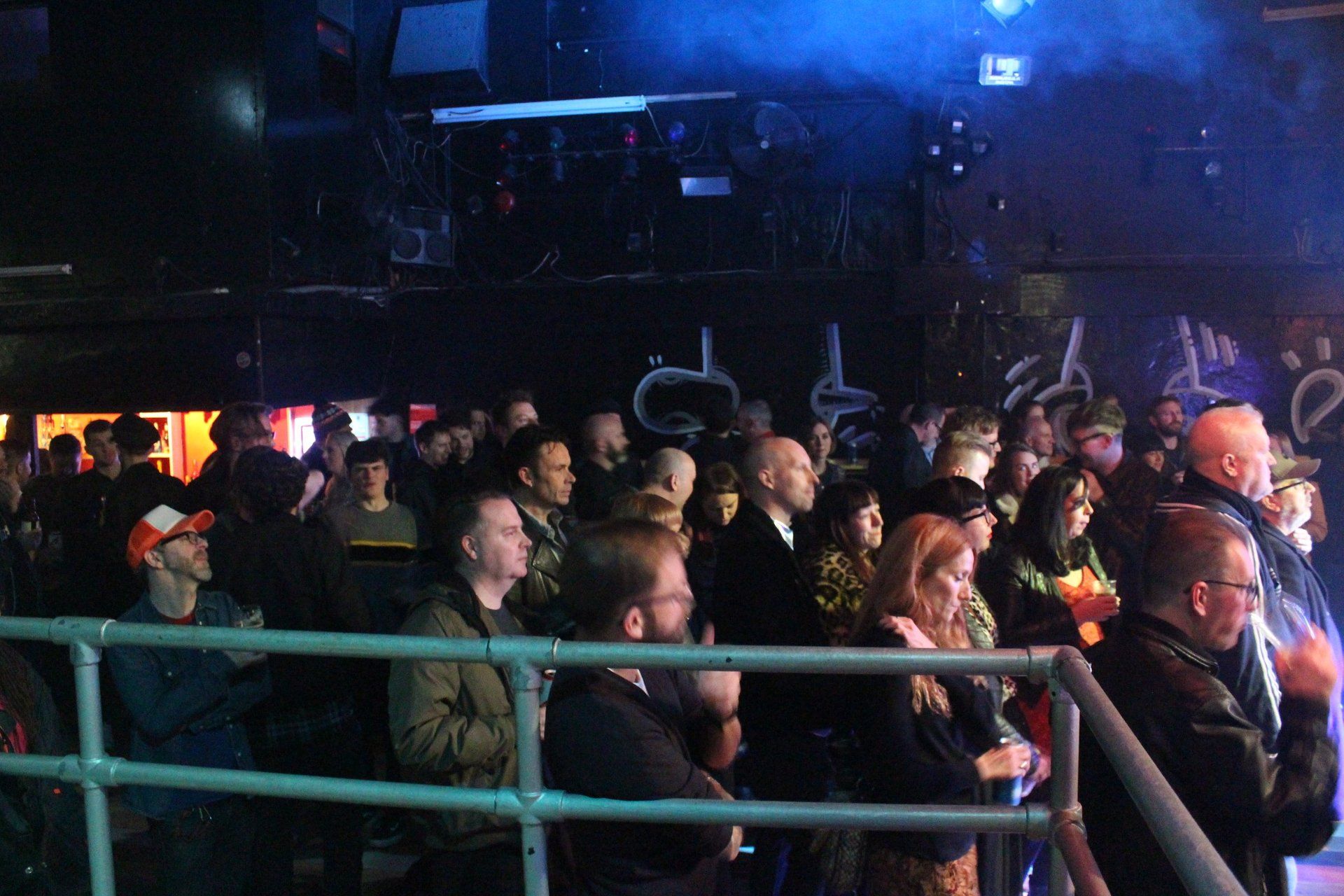 A crowd of people are watching a concert in a dark room.
