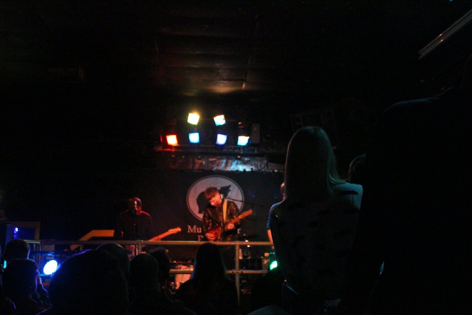 A group of people are watching a concert in a dark room.