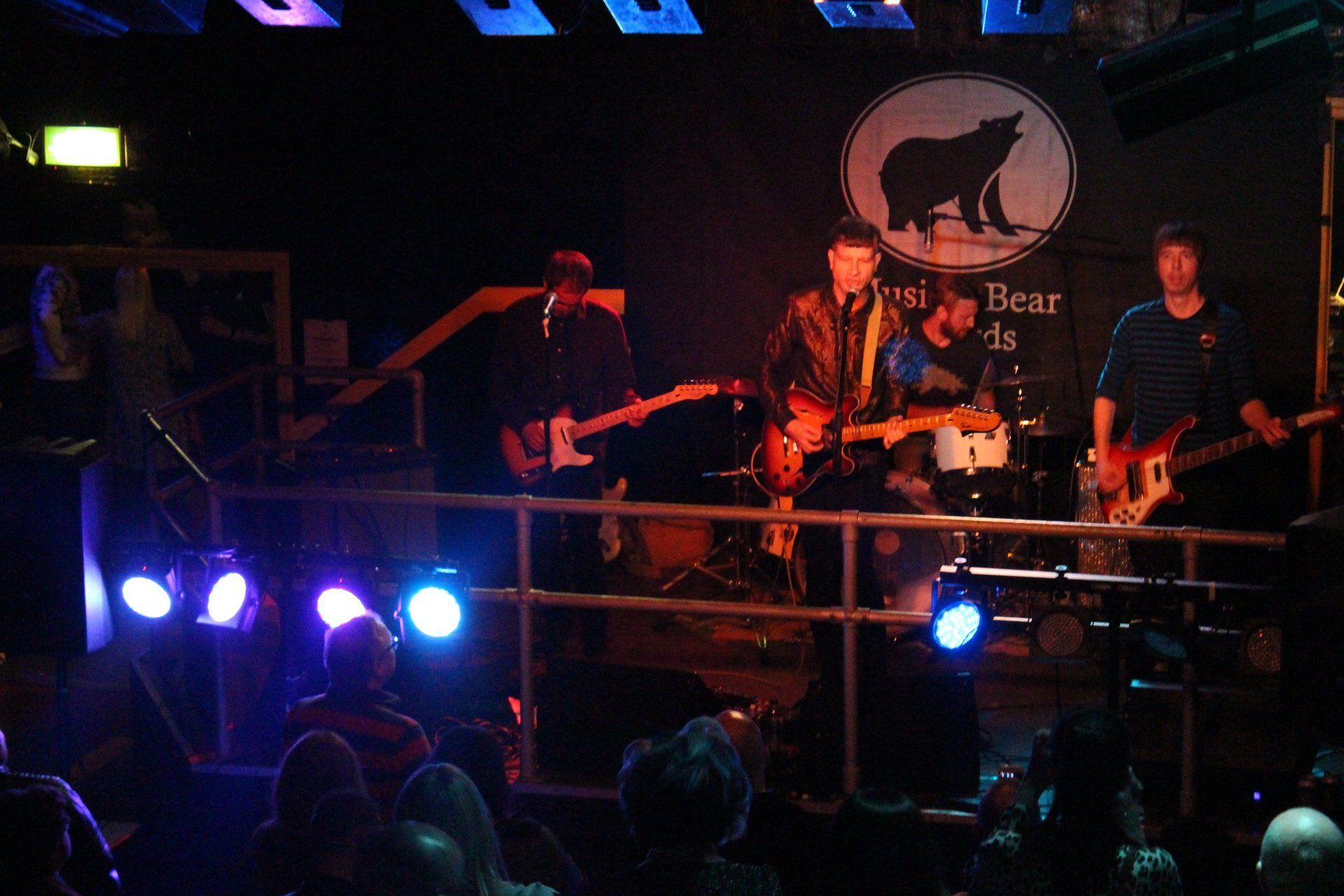 A group of people playing instruments in front of a sign that says bear