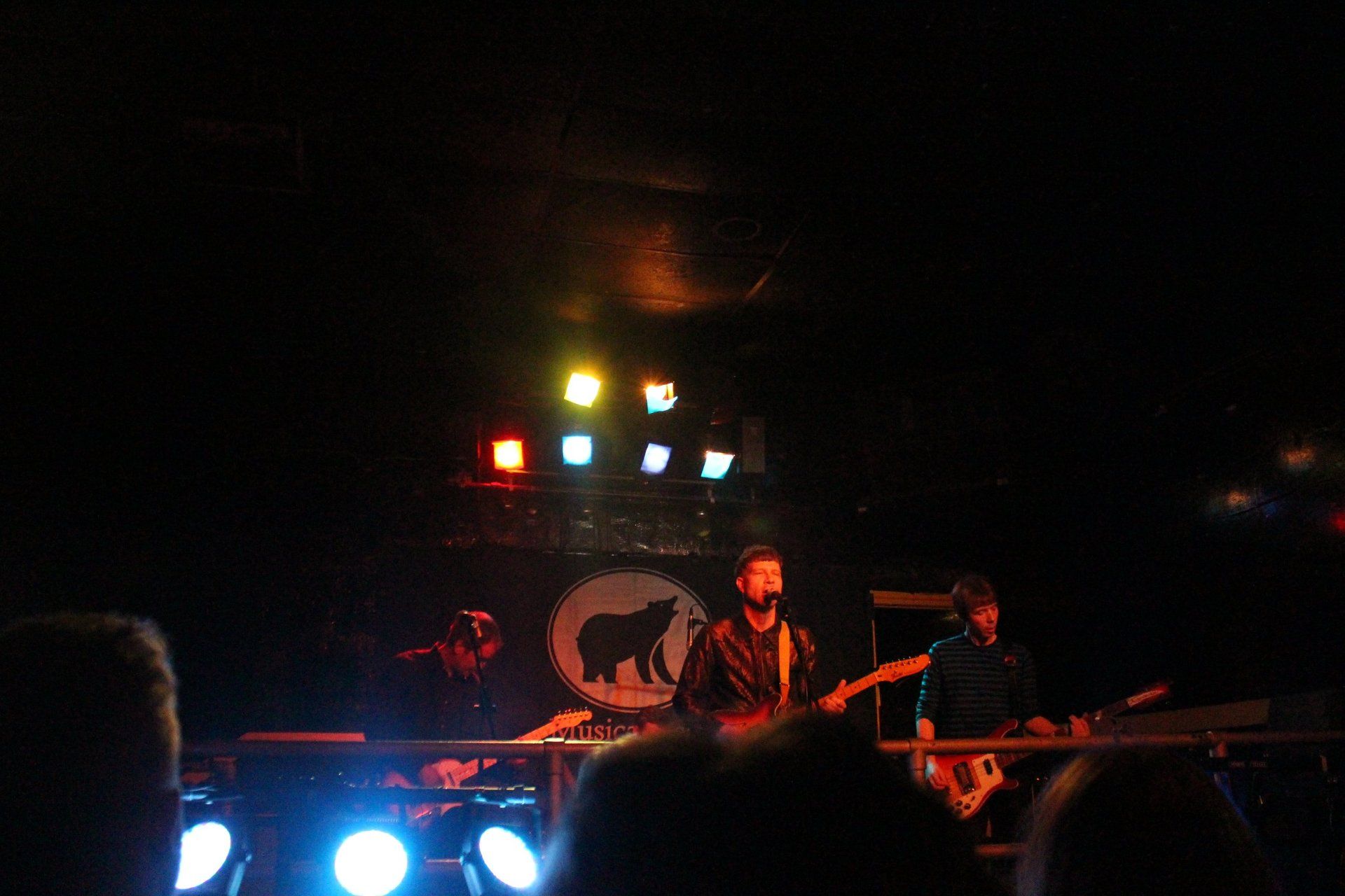 A group of people are playing instruments on a stage in a dark room.