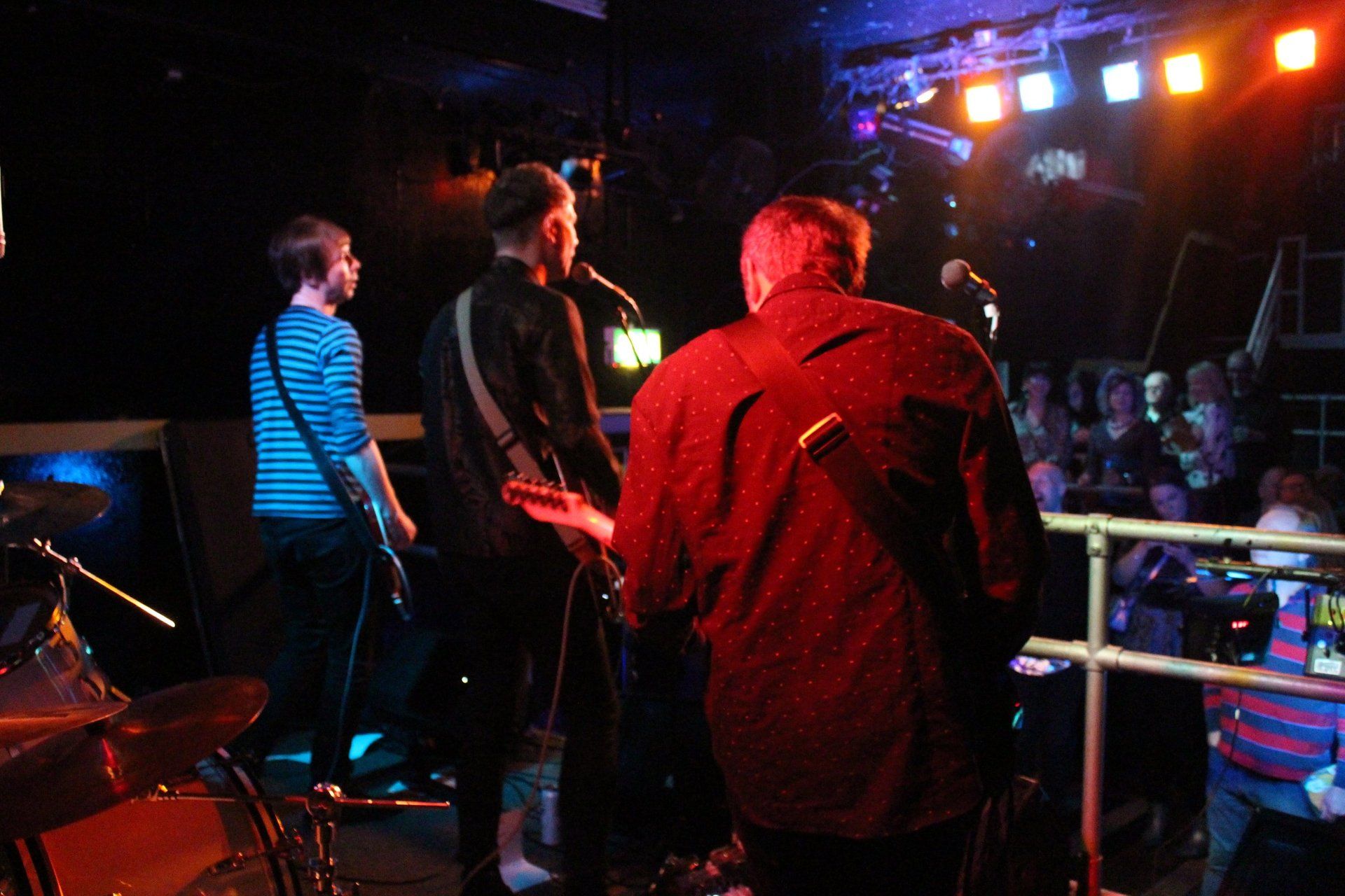 A man playing a guitar in front of a crowd in a dark room