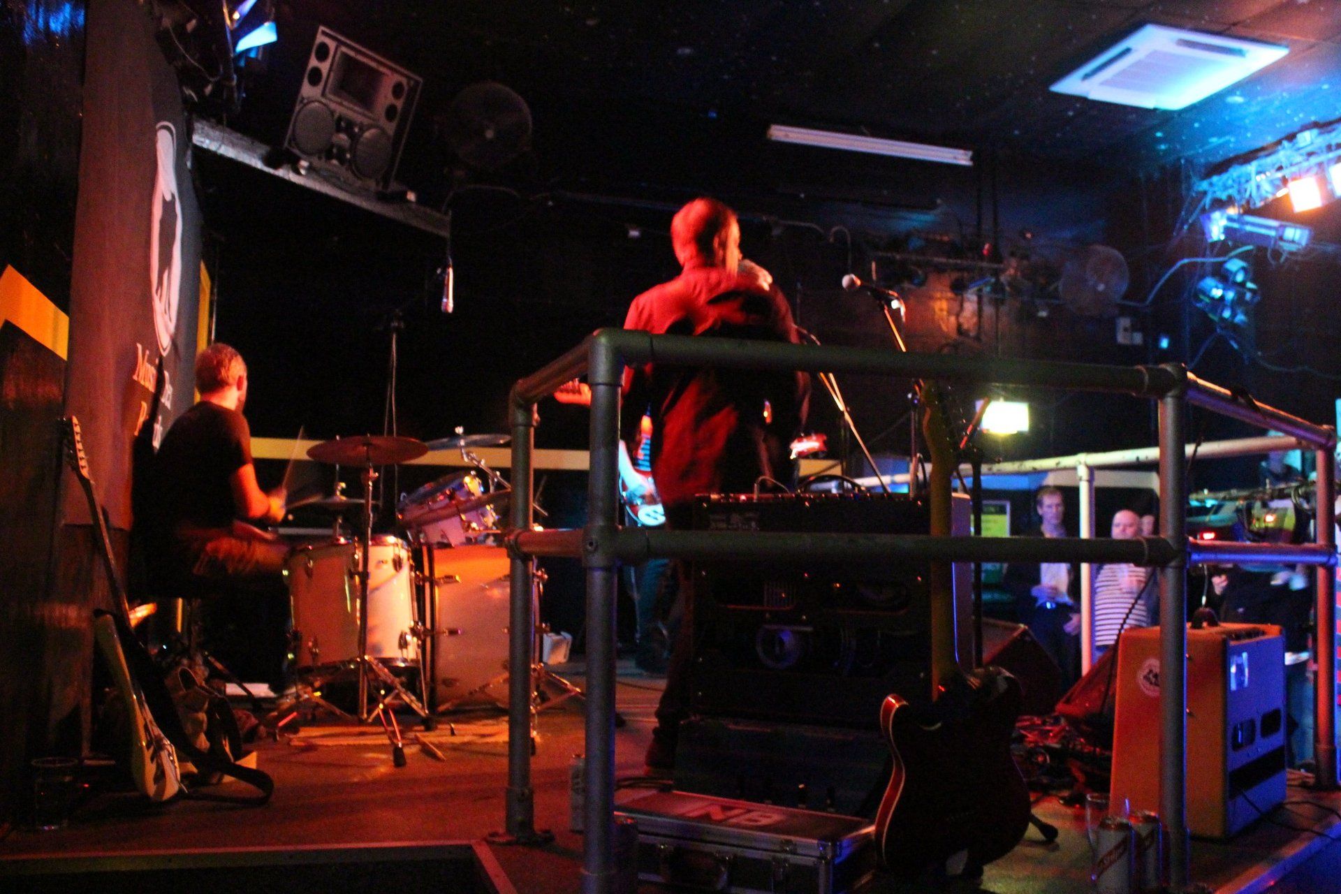 Two men are playing instruments on a stage in a dark room.