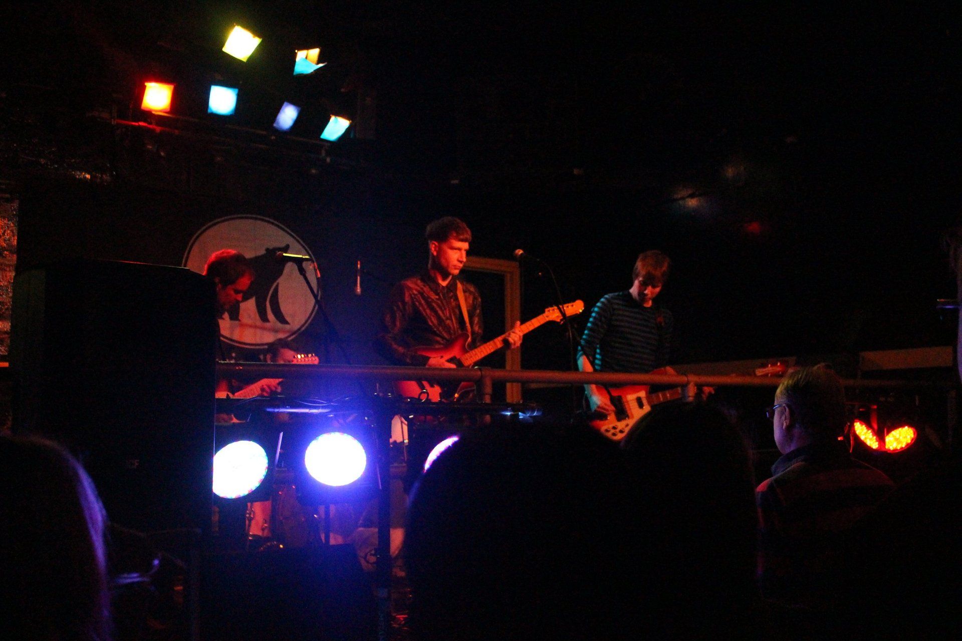 A group of people are playing instruments on a stage in a dark room.