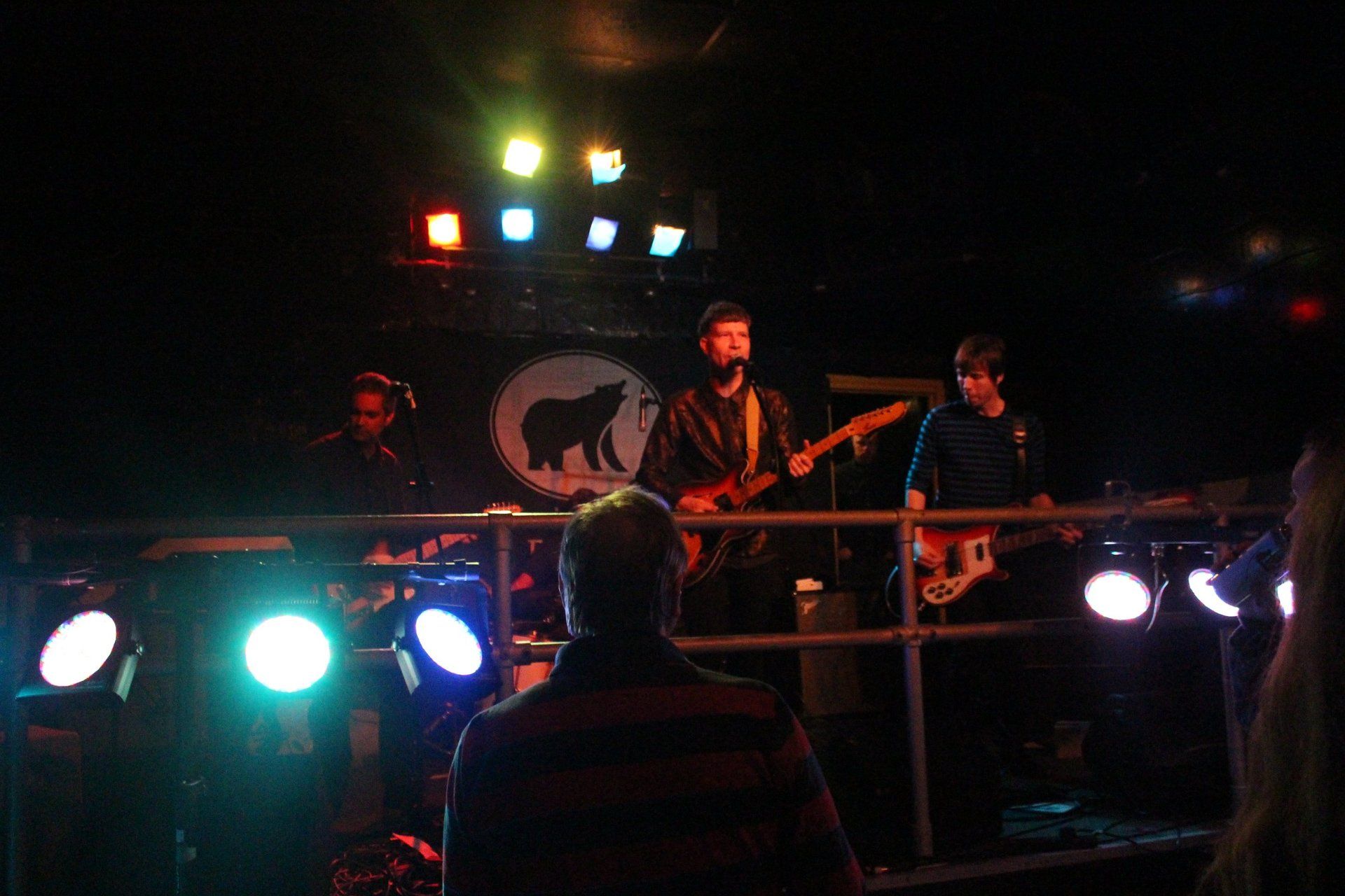 A group of people are playing instruments on a stage in a dark room.