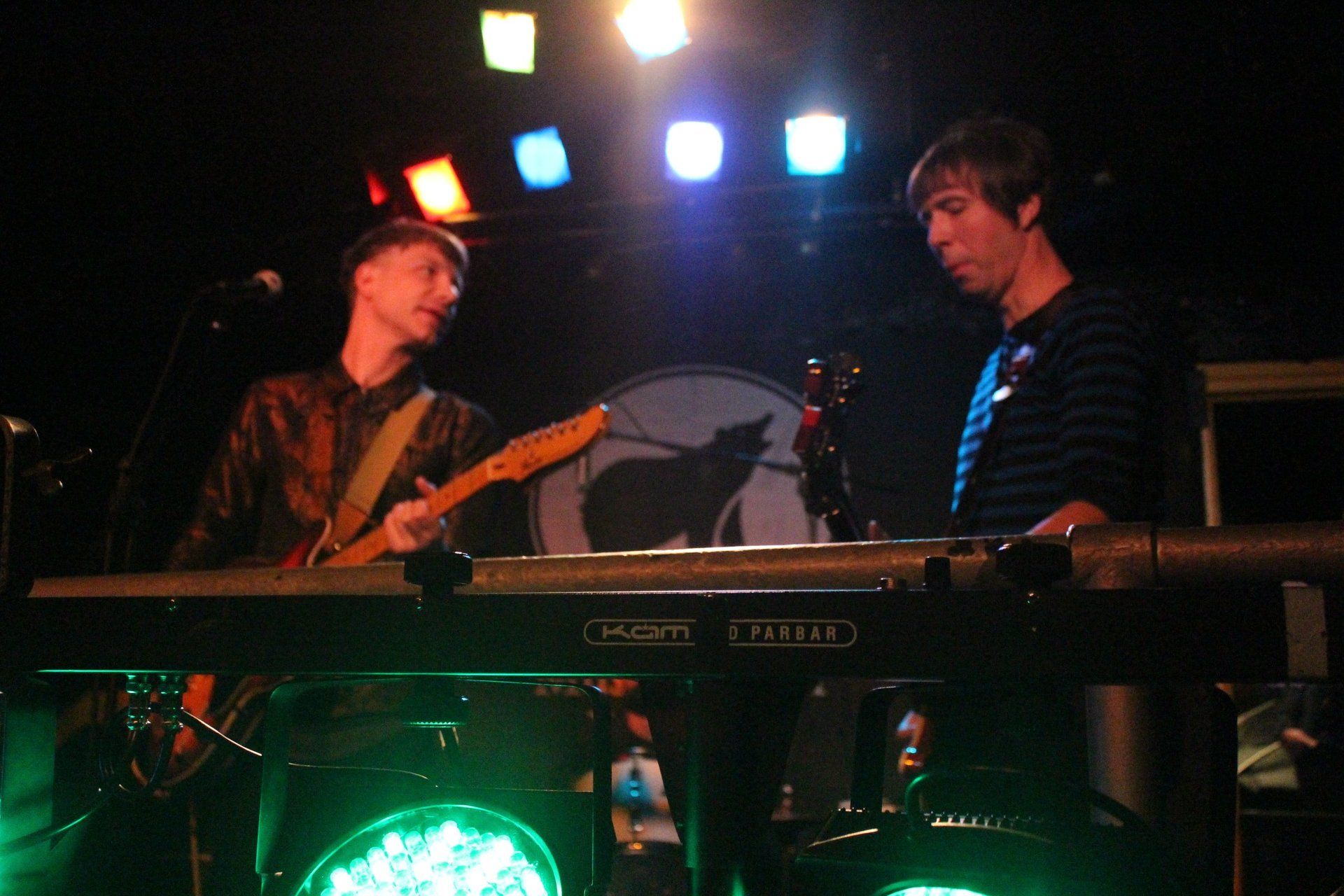 A man is playing a keyboard while another man plays a guitar on stage.