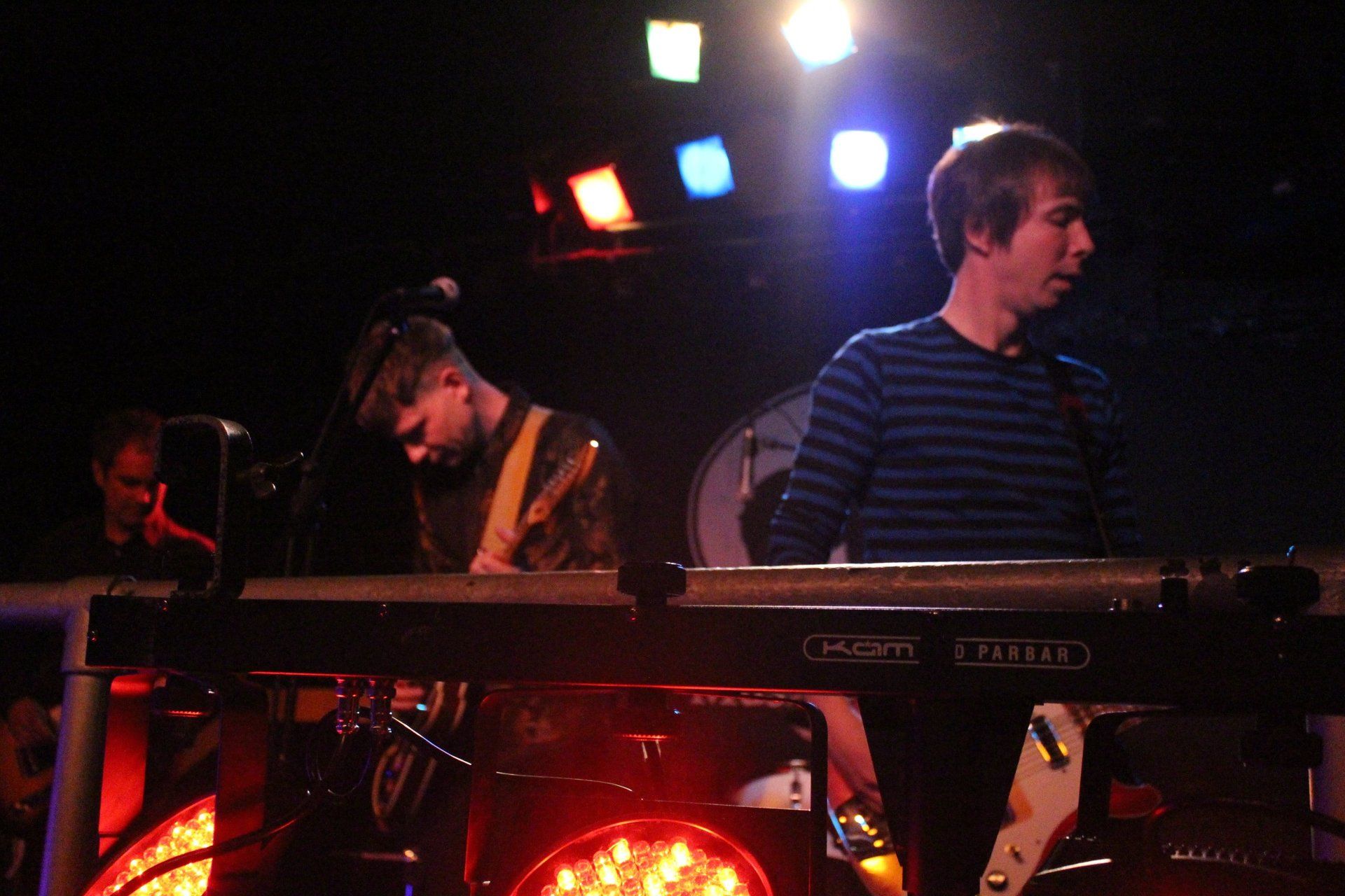 A man in a striped shirt is playing a keyboard in a dark room