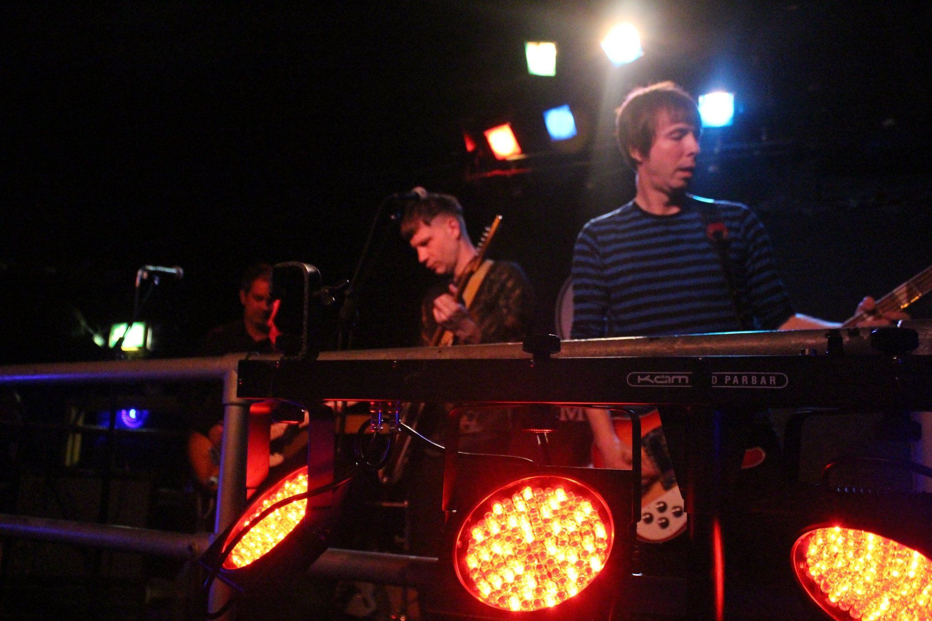 A man in a striped shirt is playing a keyboard in a dark room
