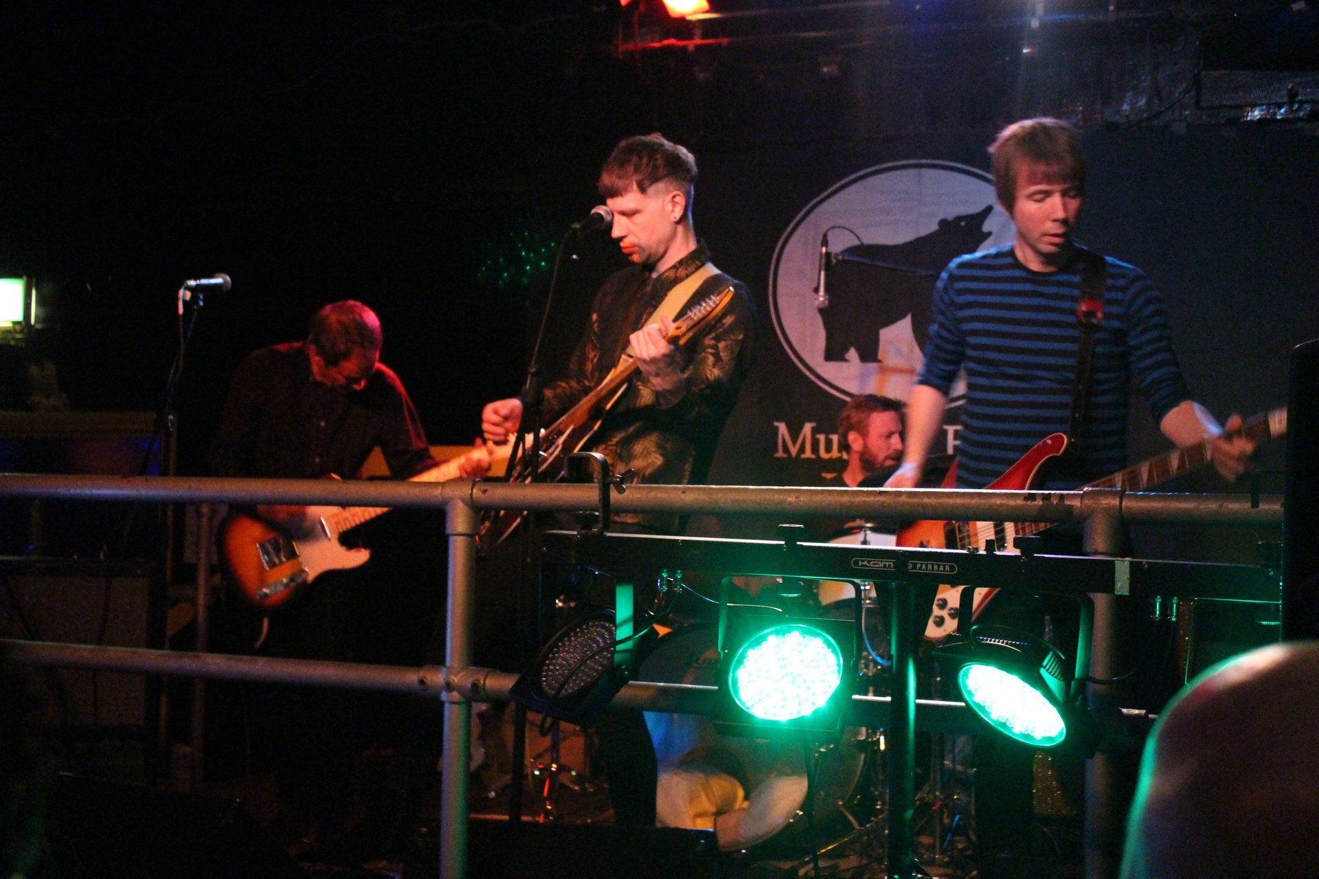 A man playing a guitar in front of a sign that says muse