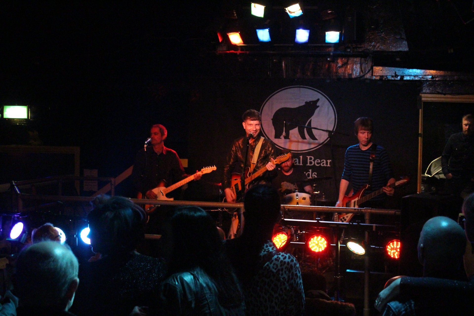 A group of people playing instruments in front of a sign that says bad bear