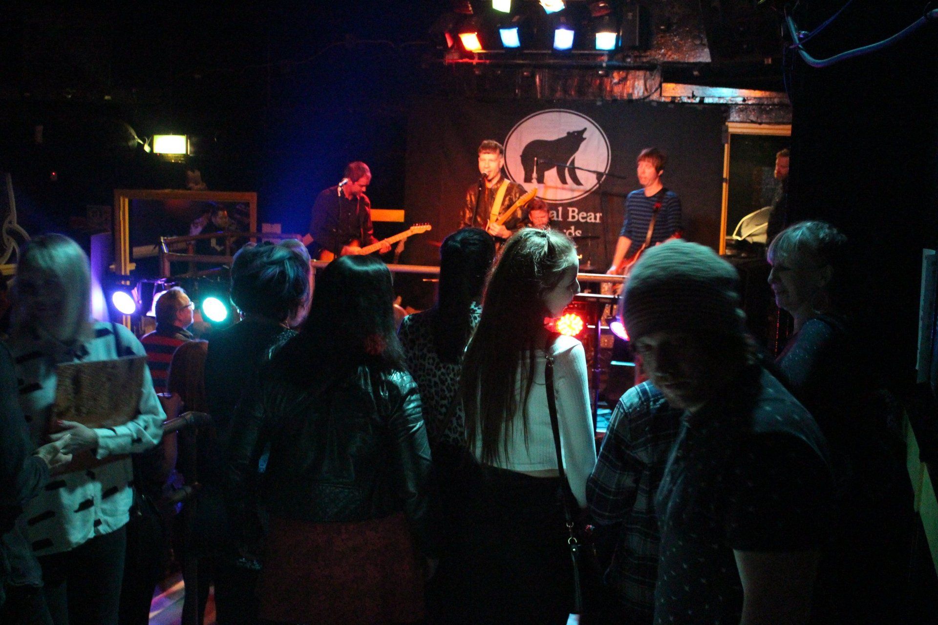 A group of people are standing in front of a stage with a bear on it