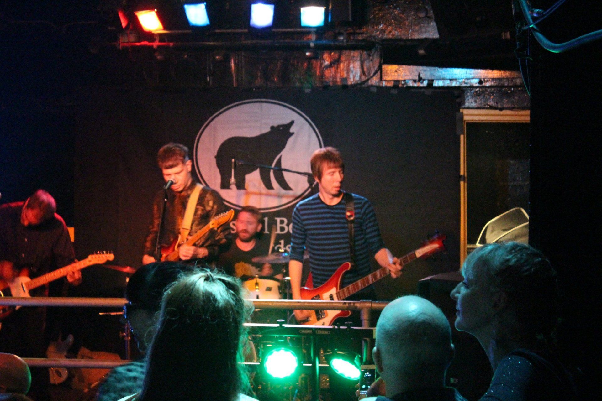 A man playing a guitar in front of a sign that says lb