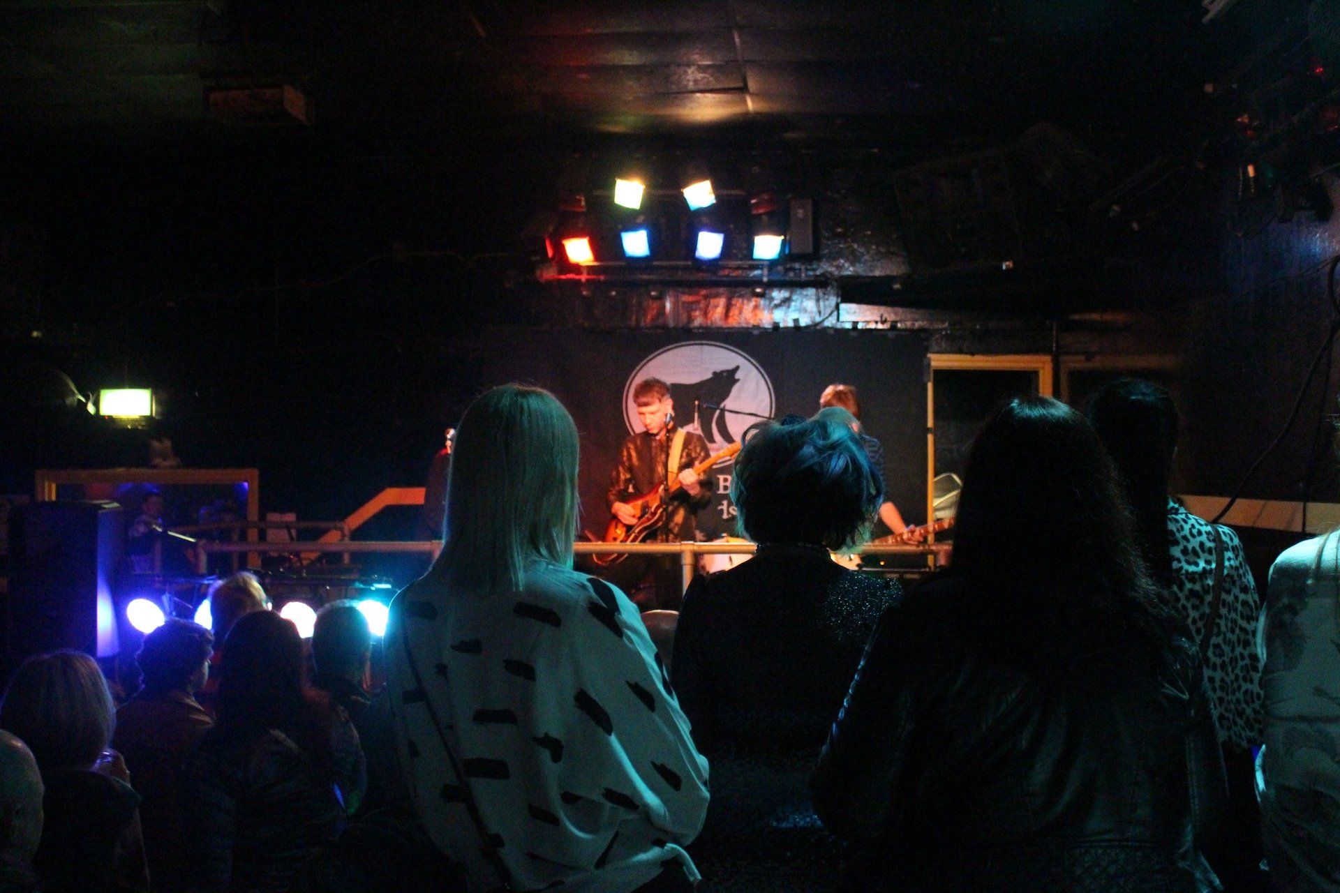 A group of people watching a band on stage in a dark room