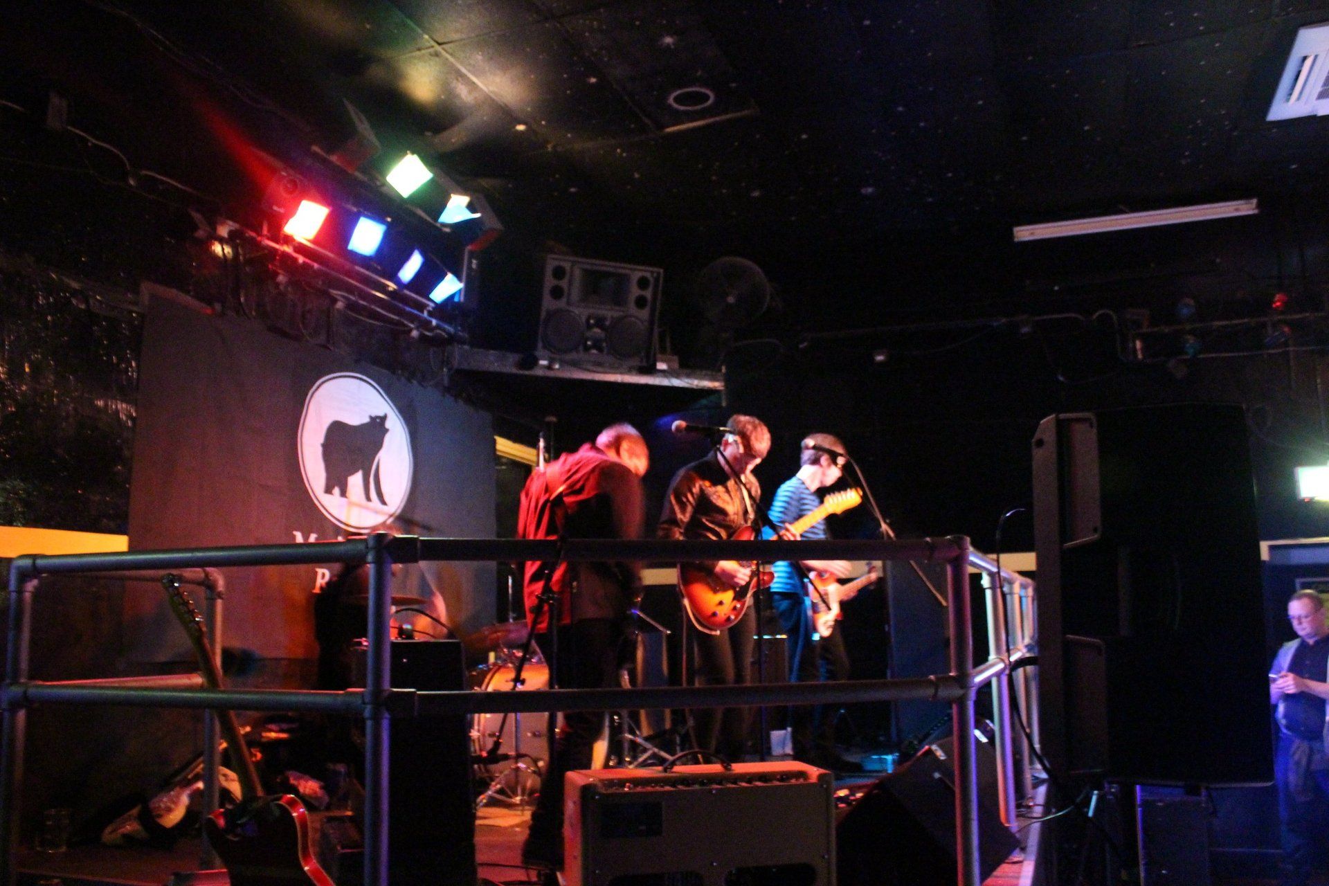 A group of people are playing instruments on a stage in a dark room.