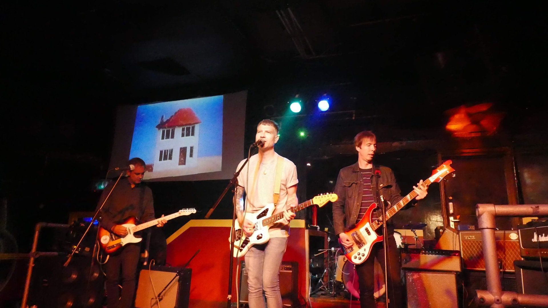 A group of men are playing guitars and singing into microphones on a stage