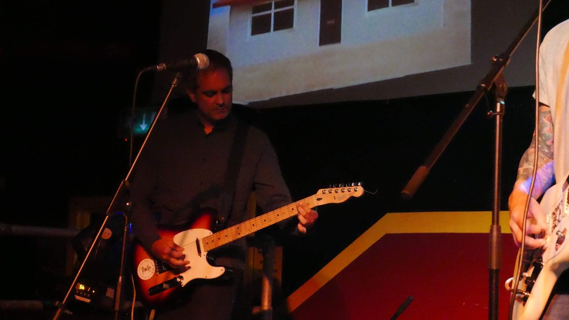 A man is playing a guitar and singing into a microphone on stage