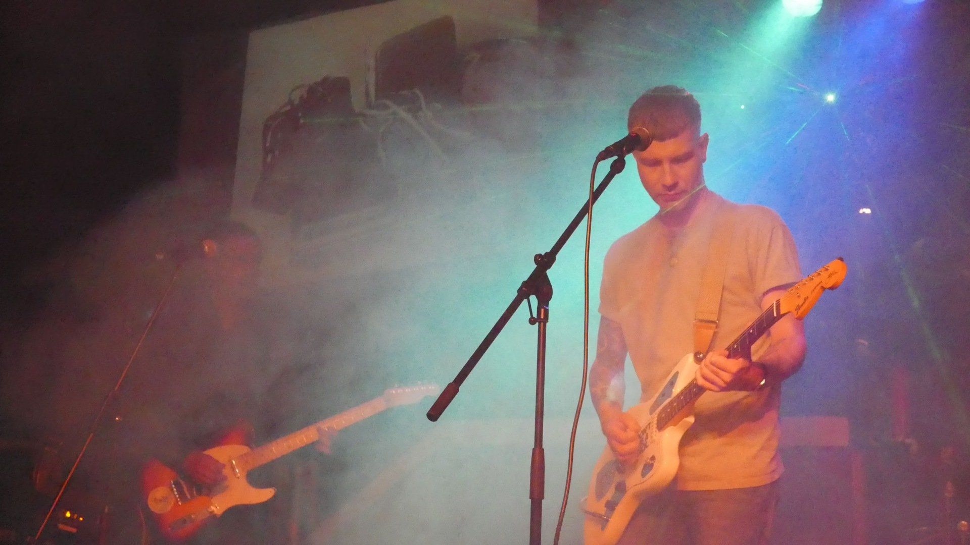 A man is playing a guitar and singing into a microphone on a stage.