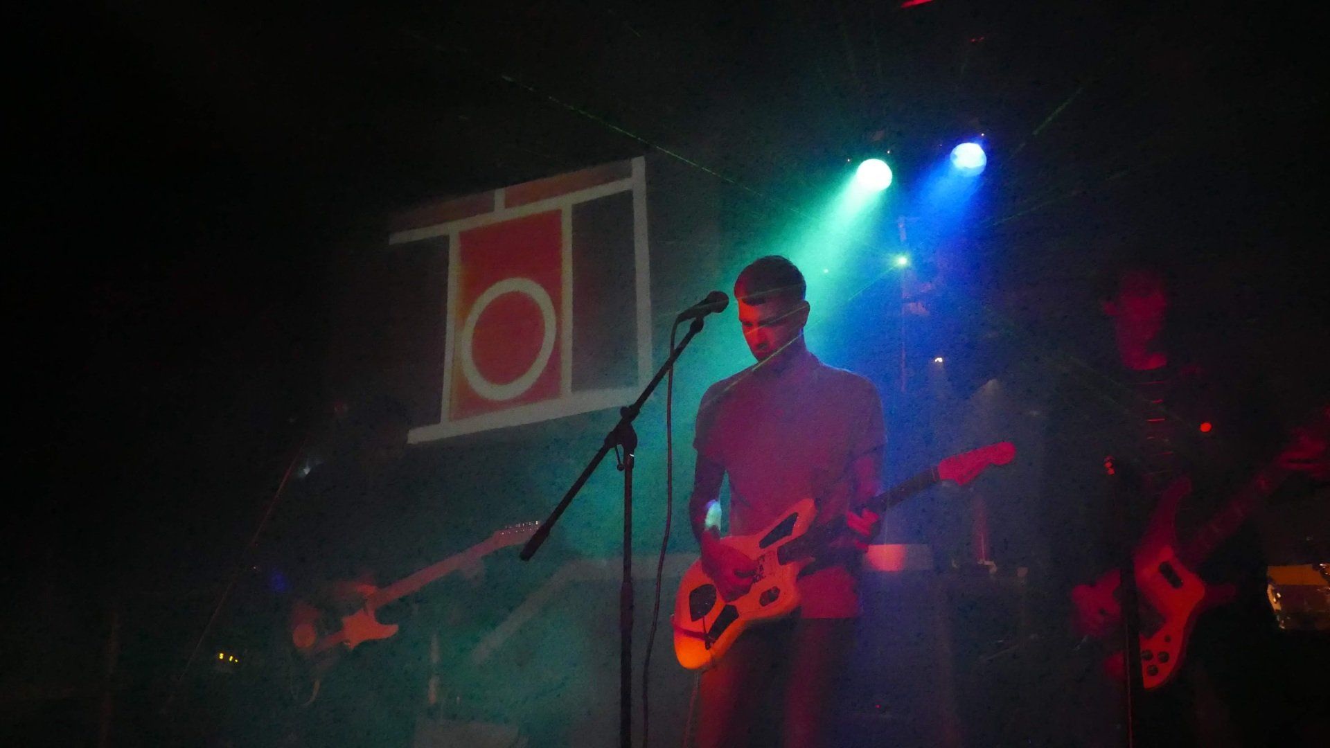 A man is playing a guitar and singing into a microphone on a stage.