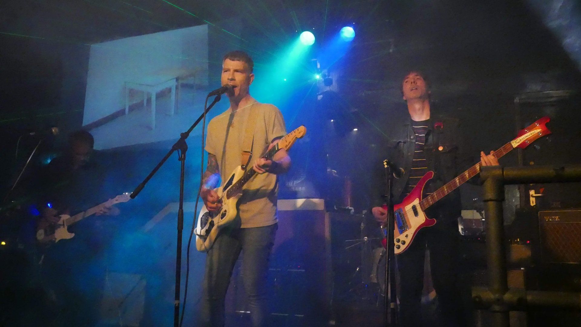 Two men are playing guitars and singing into microphones on a stage.